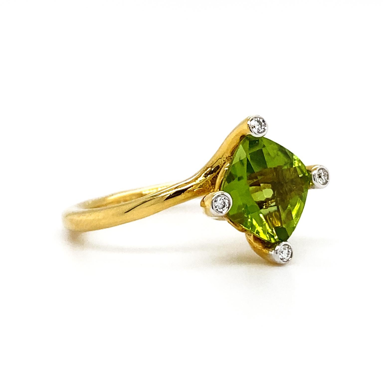 A lustrous cushion cut peridot is heightened with four bezel set brilliant cut diamonds on each corner. An 18k yellow gold band is oblique as the finishing touch. The weight of the peridot is 1.84 carats and the diamonds weigh a total of .04 carats.