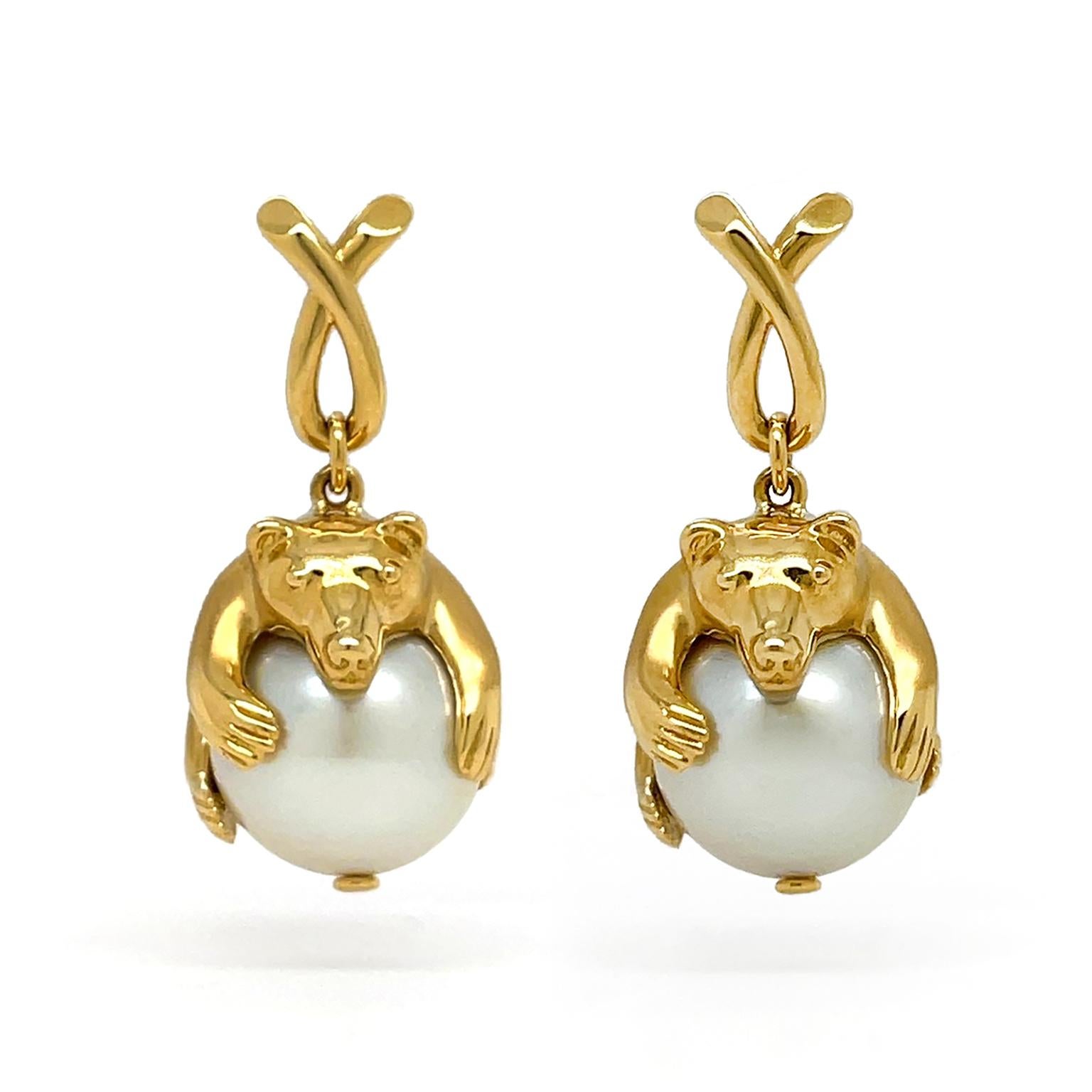 Descending from a folded loop, these polished 18k yellow gold polar bears are a unique update to classic pearl earrings. Craftsmanship includes detailed carving of the paws and eyes. The polar bears relax on top of a south sea pearl, giving the