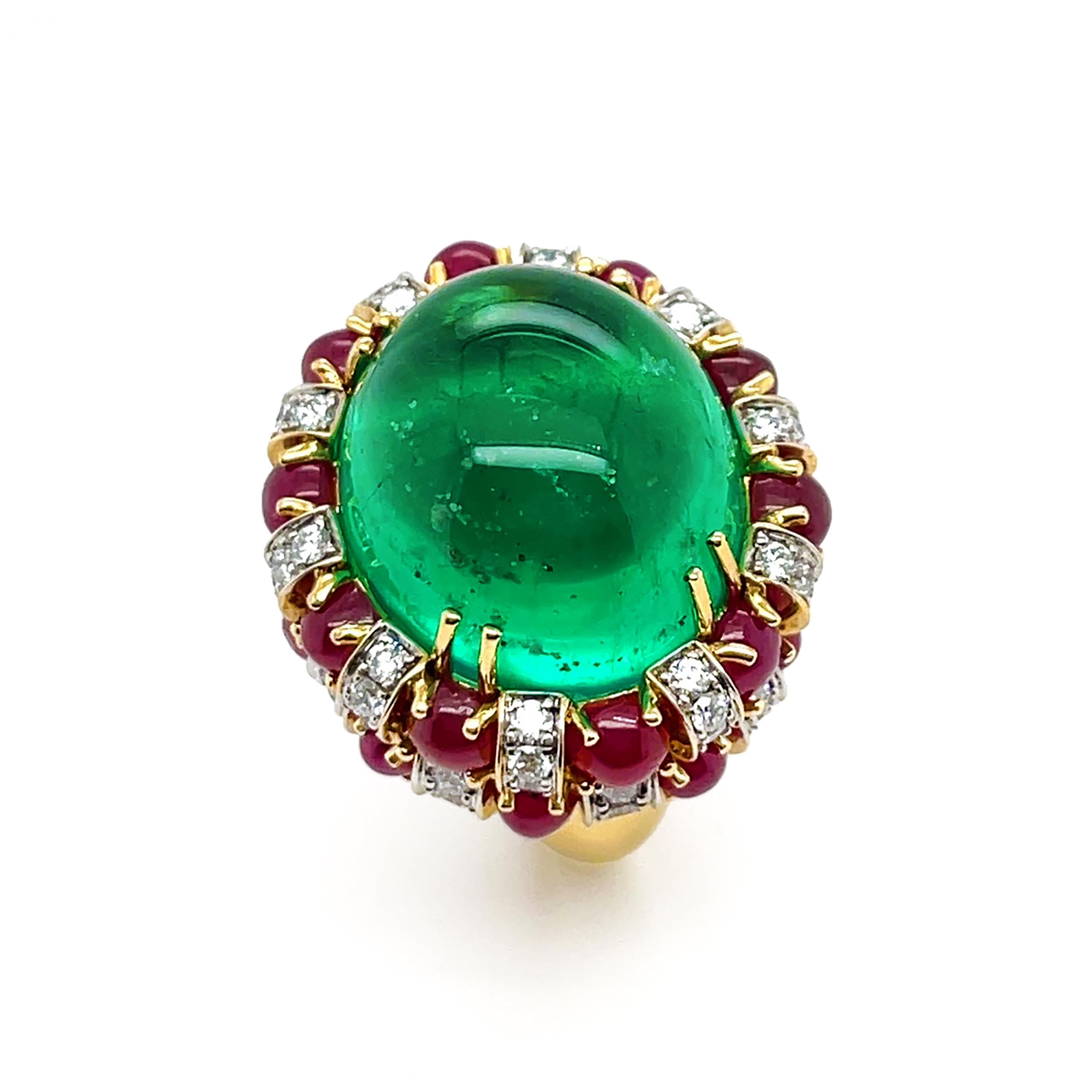 Ein kostbarer Smaragd aus Kolumbien ist das Herzstück dieses Rings. Der erhabene ovale Cabochon ist in Zacken aus 18 Karat Gelbgold gefasst und zeigt seine einzigartigen Einschlüsse. Zwei Reihen von Rubin-Cabochons und gepflasterten Diamanten drehen