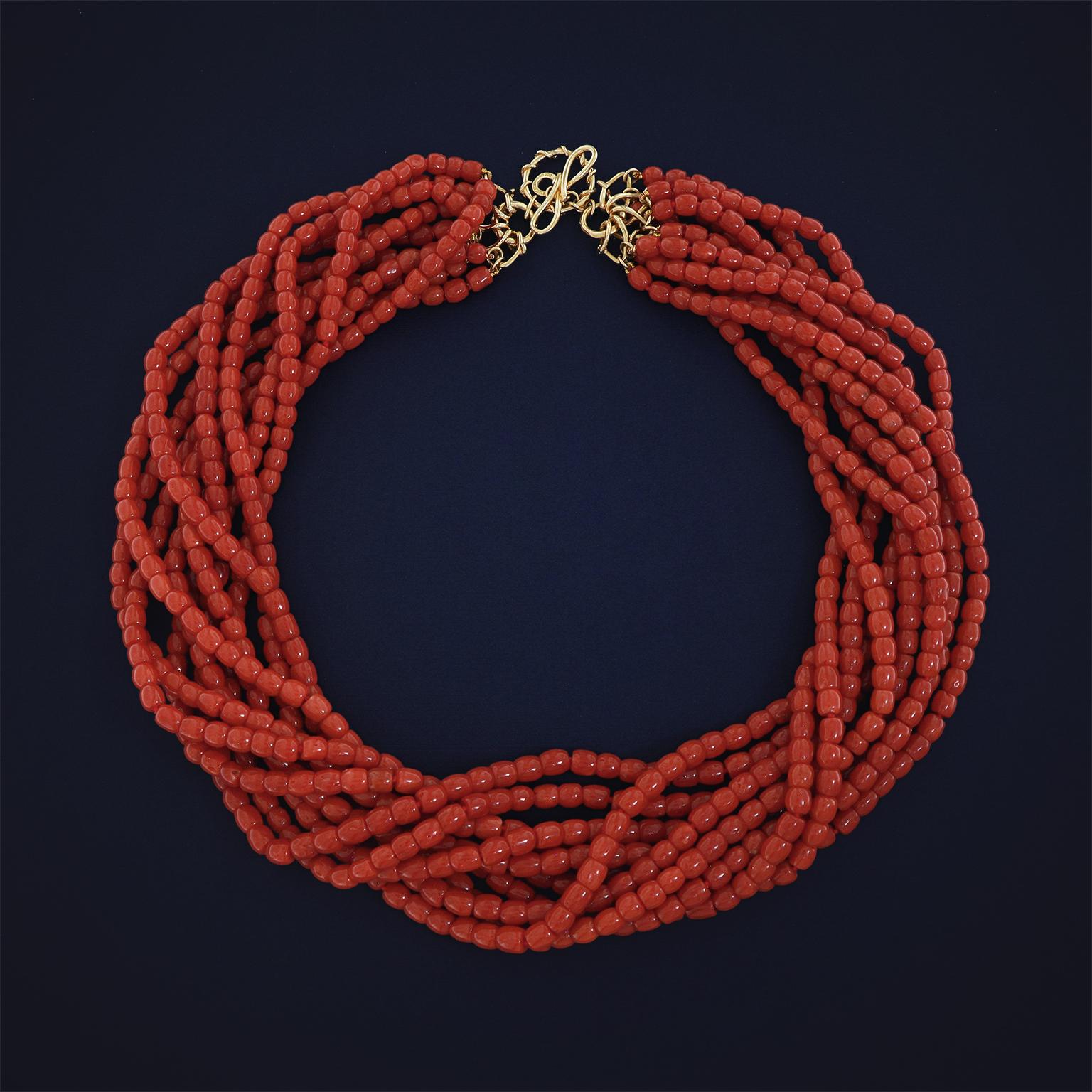 Striking intensity of Sardinian red coral is the focus of this necklace. Smooth carvings of the deep red precious gem are strung together on ten strands. Next the strands are twisted in a torsade, then joined together by V-shaped links. The total