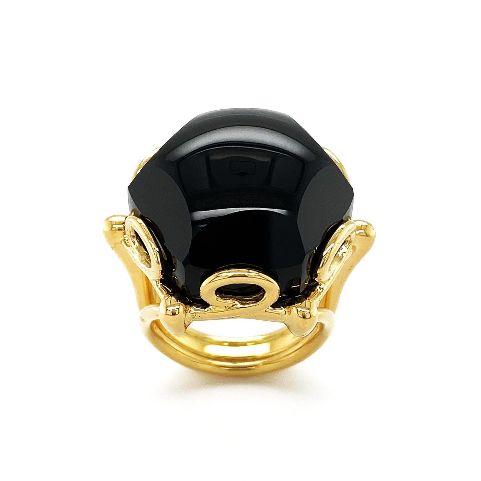 Black onyx showcases its sleek charm in this ring. 18k yellow gold loops to trim and secure the polished gem, while the triple split band provides a daring accent. The weight of the onyx is 36.06 carats and the ring measures 1.02 inches (width) by