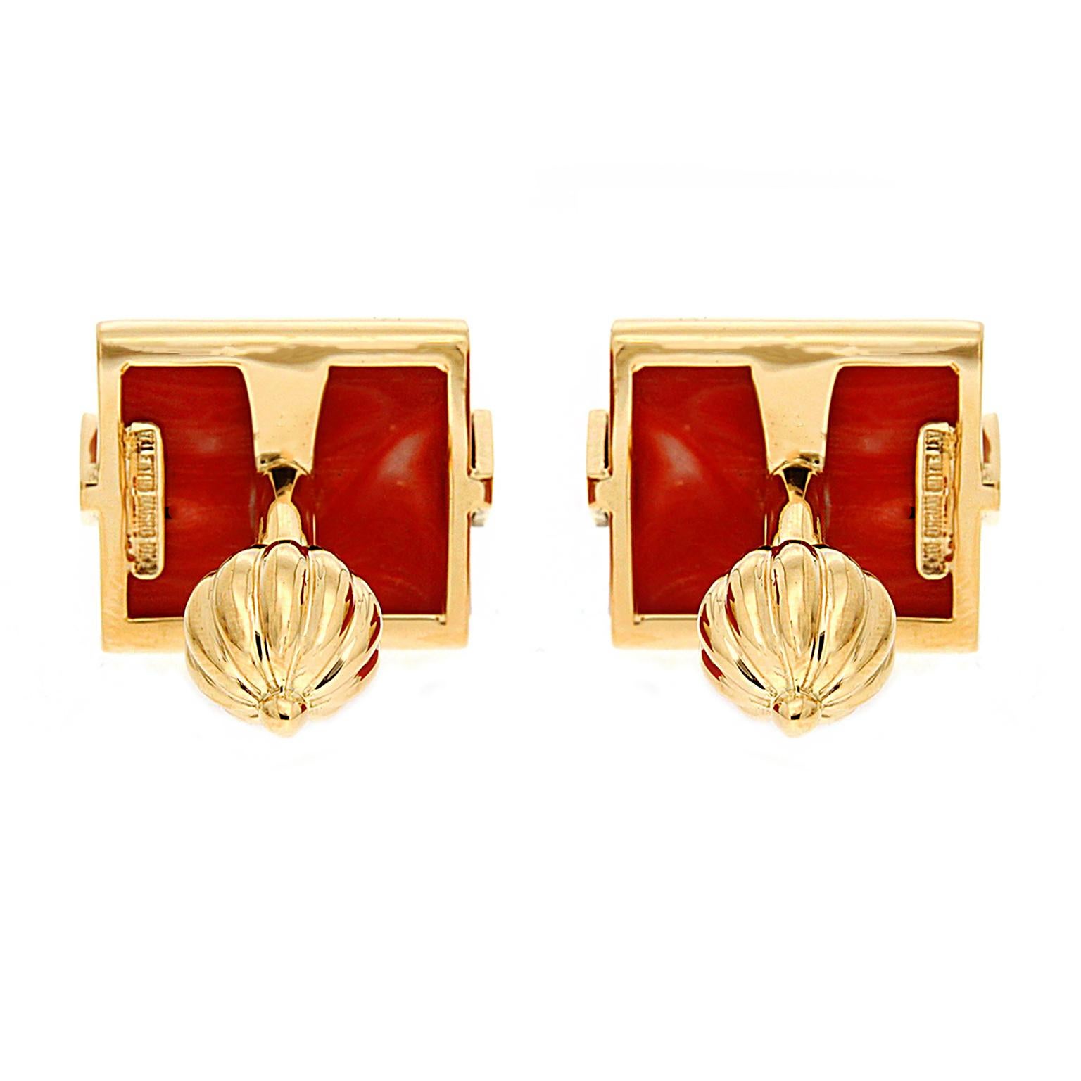 Geometric silhouettes create a prominent design. Red coral in a rectangle shape is the gem of choice, while 18k yellow gold triangles on the sides underline the vivid color of the coral. The total weight of the gem is 33.38 carats. A bar and ribbed