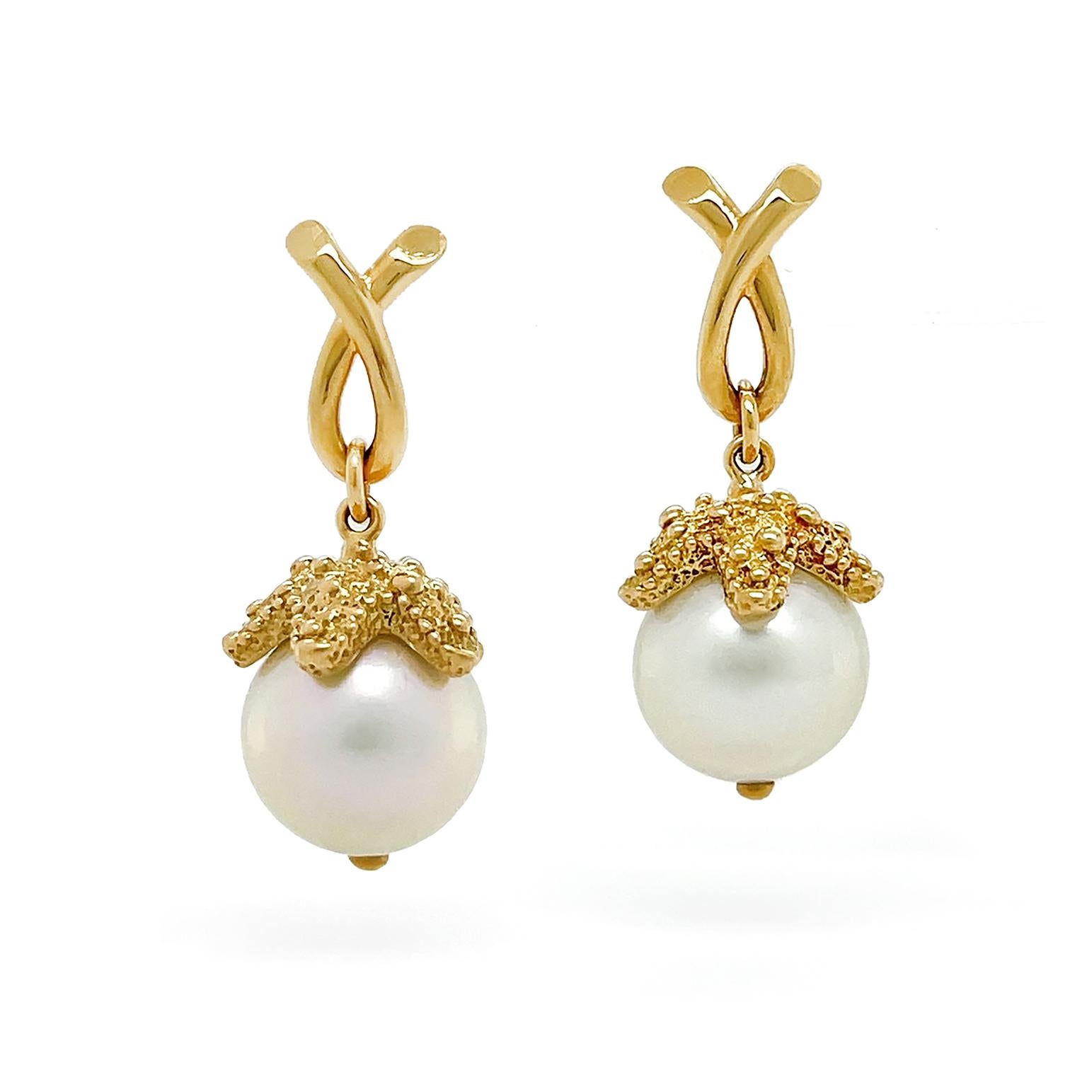A vibrant starfish embraces a pearl for these drop earrings. An 18k yellow gold loop descends a starfish made of the same metal. The craftsmanship of a textured body contrasts with the smooth round south sea pearl sheltered beneath. The total weight