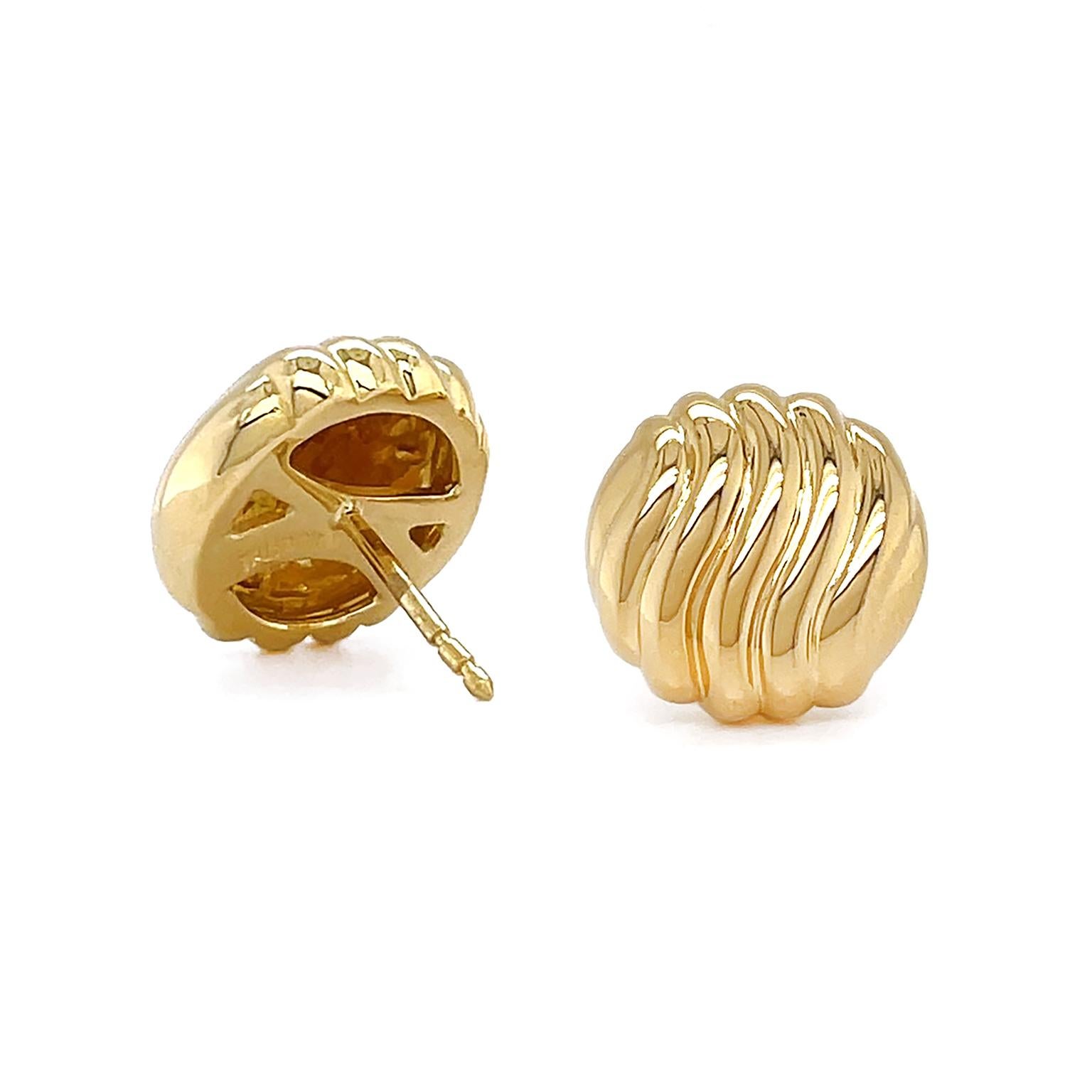 Timeless monochromatic gold earrings are given a glamorous update. A round 18k yellow gold base features rows of raised lines that curve in soft waves. The waves are polished and reflect the light and shadows that are cast on them. Clip-backs secure