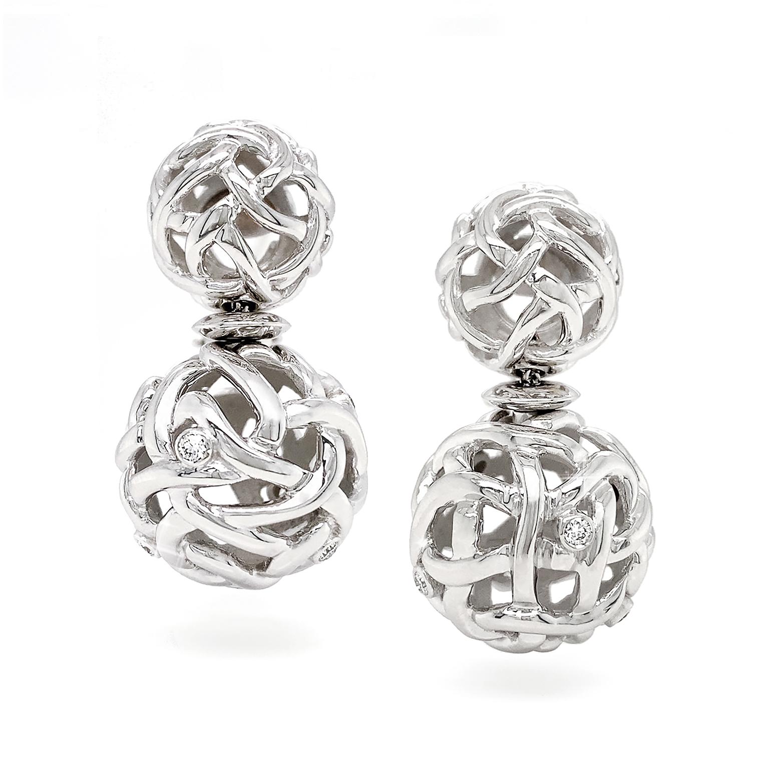 These earrings are an interlaced design of openwork orbs consisting of 18k white gold. On the larger orbs are carefully placed diamonds which bring a luminescent result. A total of 14 brilliant cut diamonds weigh .42 carats. The earrings measure .78