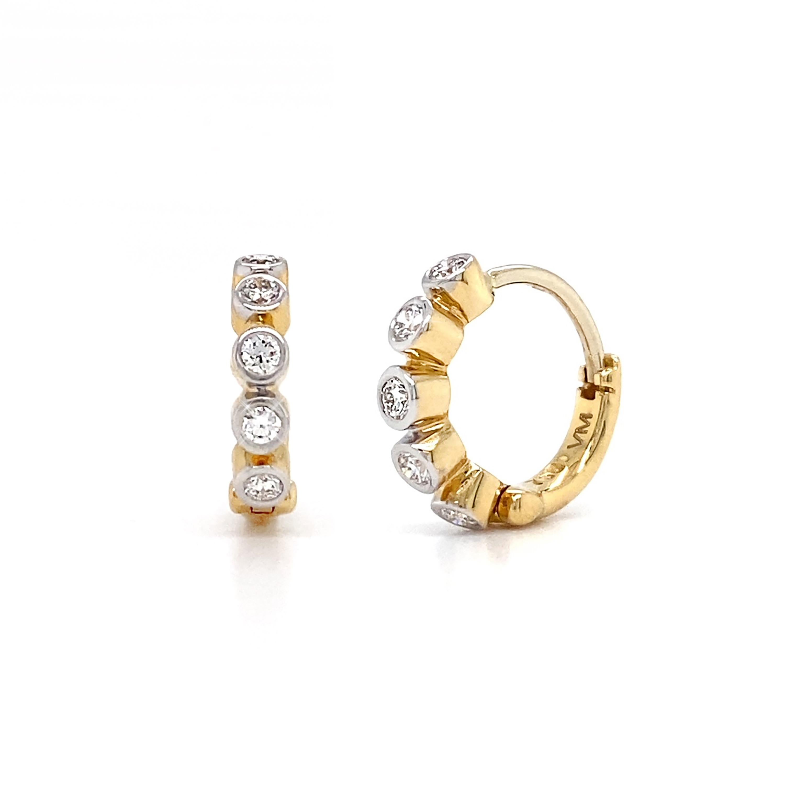 The gleam of diamonds enhances these 18k yellow gold hoop earrings. White light flickers from diamonds individually bezel set in a circular row. The total weight is 0.24 carats of diamonds. A hinge closes the earrings, forming a hoop that hugs the