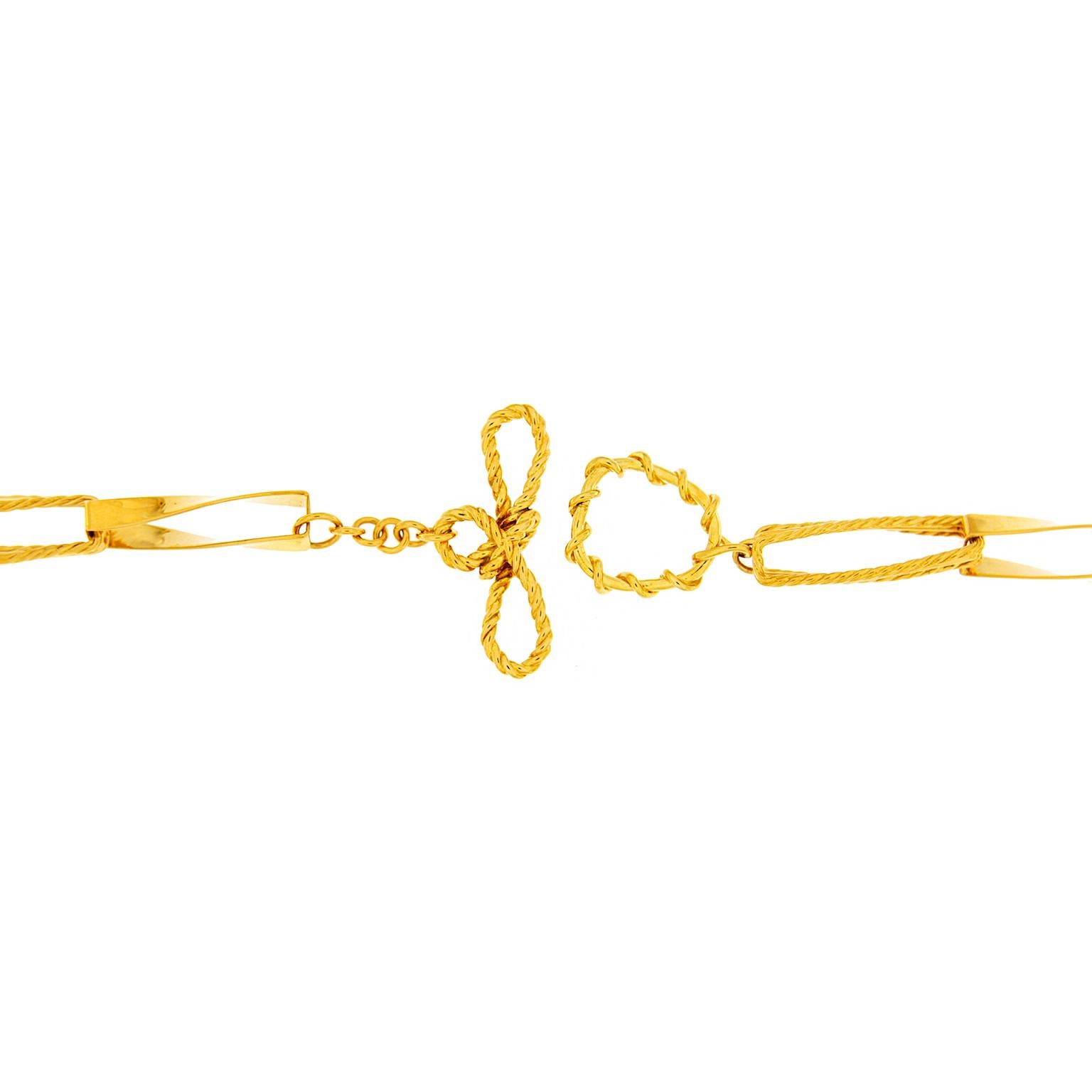 Warm-hued metal of 18k yellow gold forms interlaced ribbons. Connected in sections, each element is a flat slender overlapped ribbon. An alternating pattern of sleek metal followed by textured creates visual interest. The result is the impression of