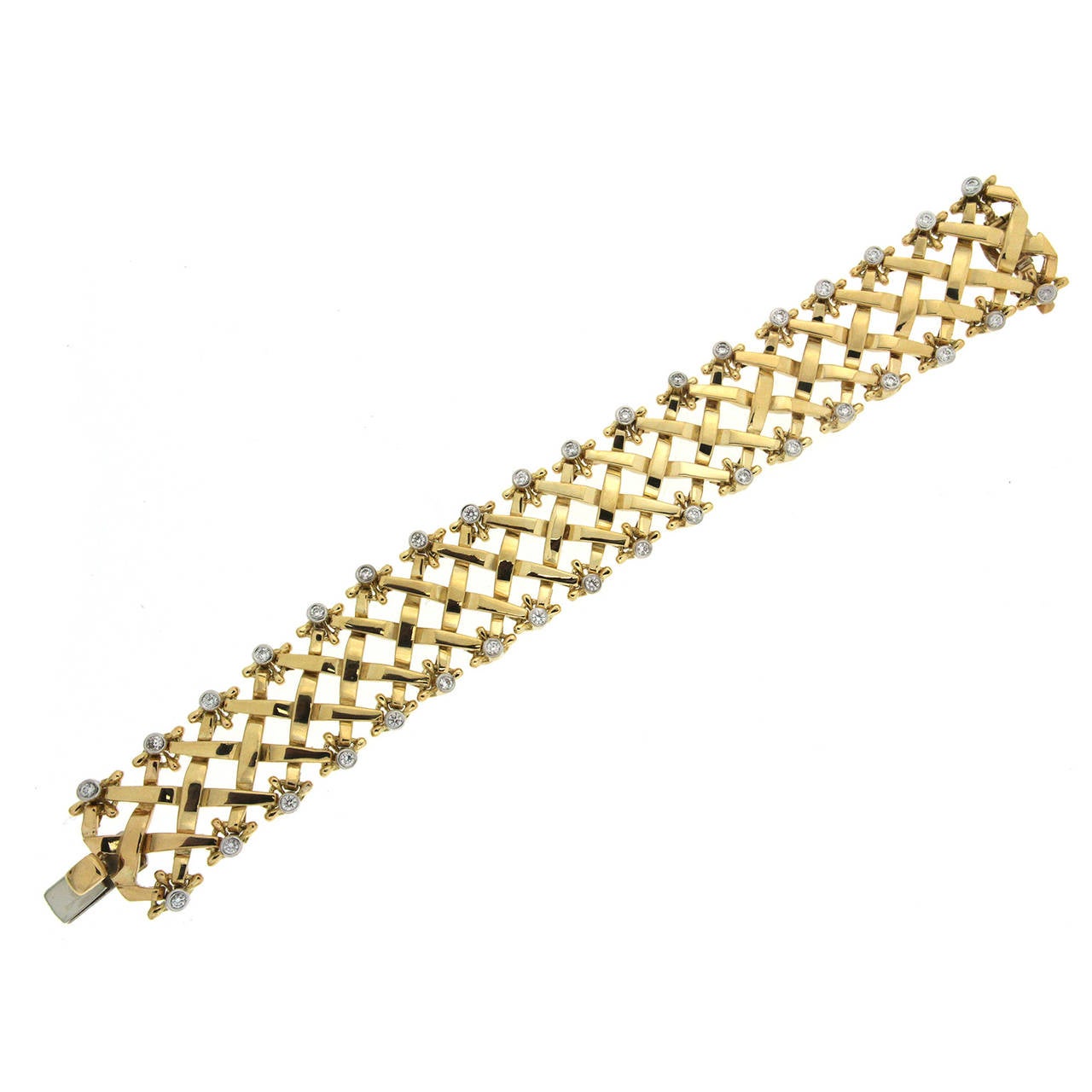 Valentin Magro Yellow Gold Woven Bracelet with Diamonds features a twist on the weave motif. Rather than straight up or down, the 18k yellow gold strips are at an angle. The tips at the edges of the bracelet boast ball designs surrounding round