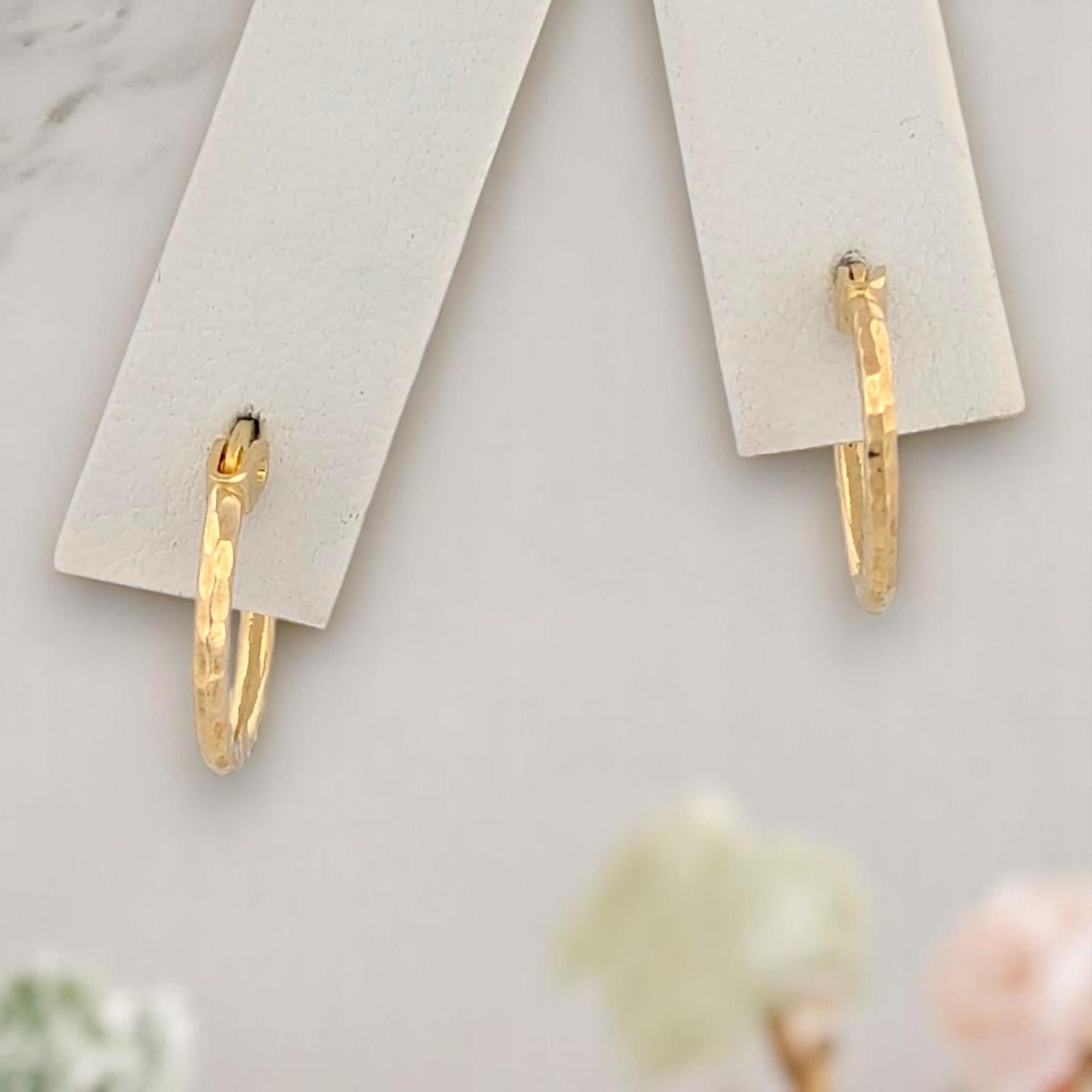 Die Valentina Hoop Earrings verbinden handwerkliche Textur mit zeitloser Eleganz. Die aus warmem 14-karätigem Gelbgold gefertigten 1/2-Zoll-Reifen weisen ein handgehämmertes Design auf, das das Licht mit organischem, fühlbarem Charme einfängt. Diese