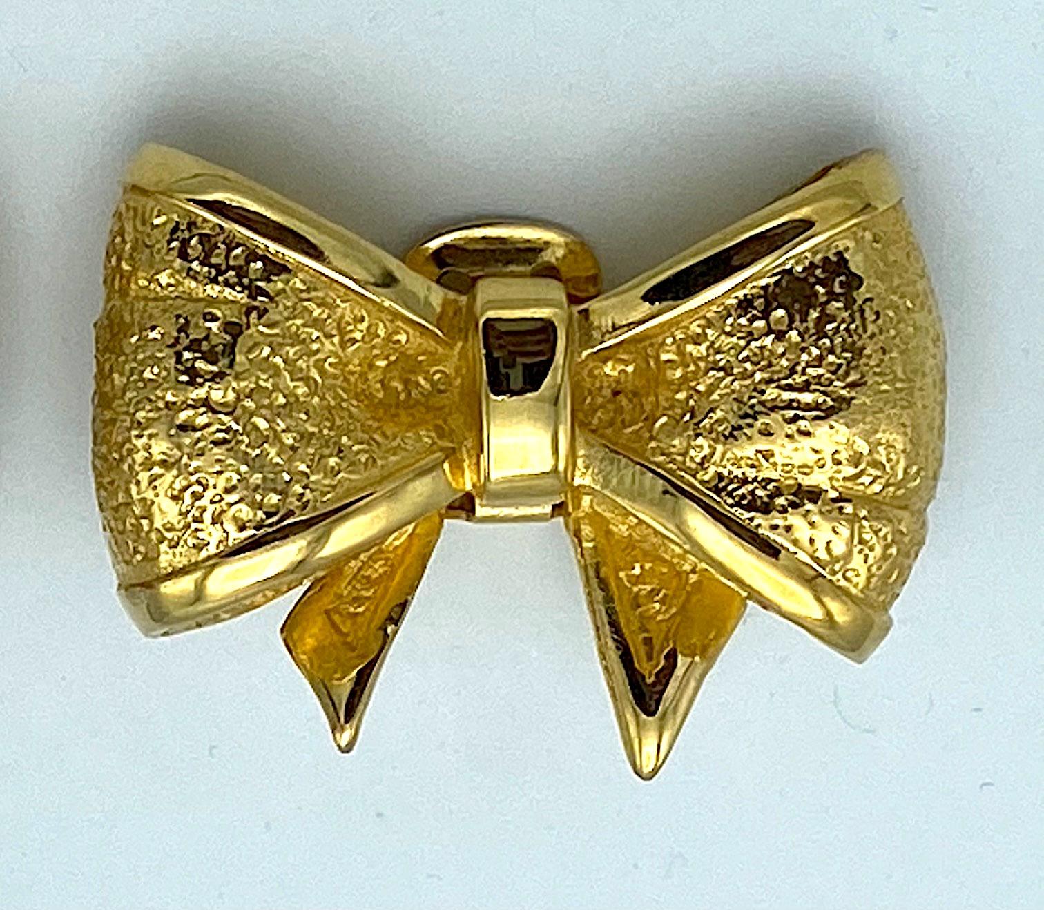 Lovely pair of 1980s Valentino bow earrings. The ribbon bow design is cast in a textured finish with a smooth border. Each gold plated clip back earring measures 1.75 inches wide, 1.13 inches high and .38 of an inch deep. Each has the oblong