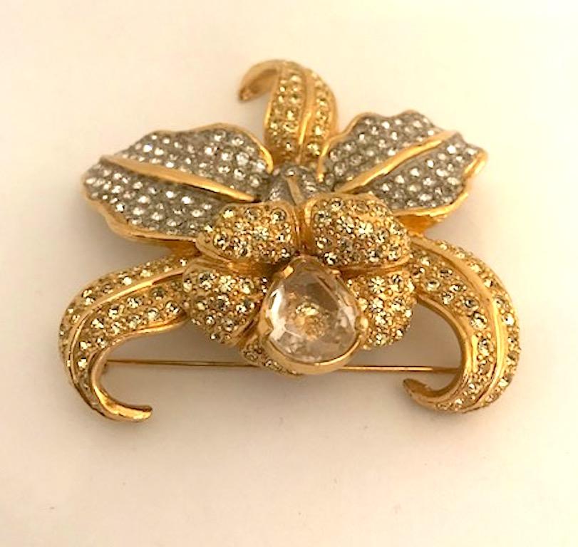A an absolutely stunning large orchid brooch by Valentino circa 1980/1990. Beautifully constructed and three dimensional in gold plate with clear and jonquil yellow rhinestones and a large pear shape unfoiled crystal stone. The brooch measures 3.13