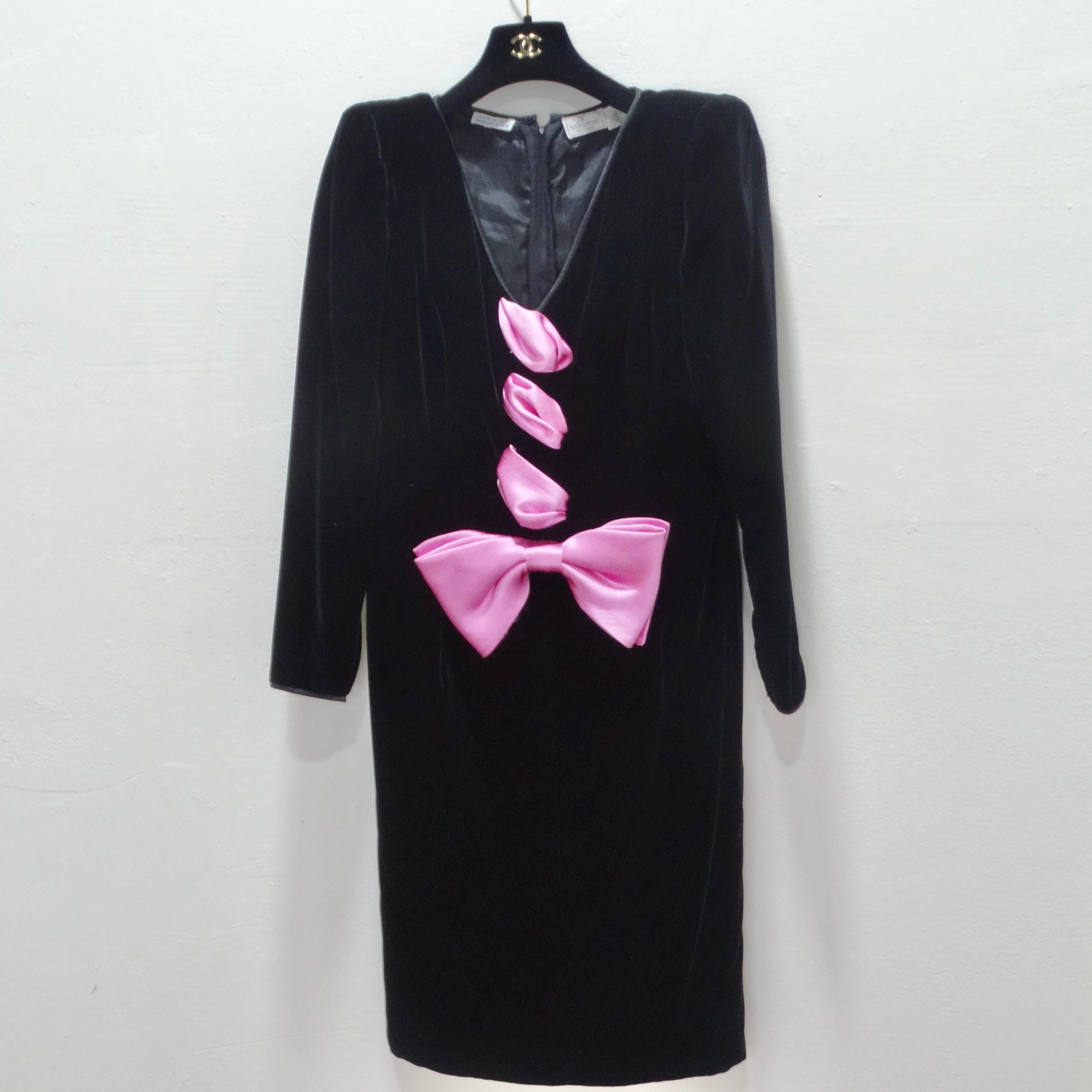  Are you ready to make an unforgettable entrance? Embrace the electrifying style of the 1980s with our Vintage Valentino Pink Bow Dress, an iconic piece that embodies the essence of the era. This black velvet mid-length dress features long sleeves,