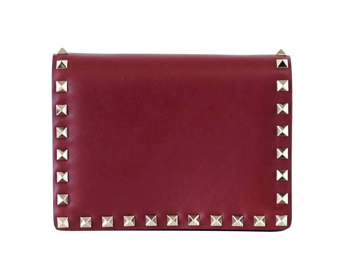 Guaranteed authentic Valentino Garavani Mini Rockstud Cross Body wallet on a chain. 
Signature Rockstud hardware with hidden magnetic closure.
Fine gold chain tucks away to wear as clutch. 
Front flap pocket when opened.
Interior has zipper pocket