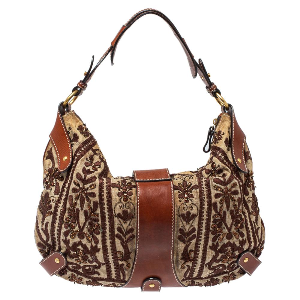 This eye-catching hobo from Valentino is crafted from embroidered canvas and leather. It features the brand's V logo detailed on the front, a single shoulder handle, and gold-tone hardware. The spacious interior can carry all your daily