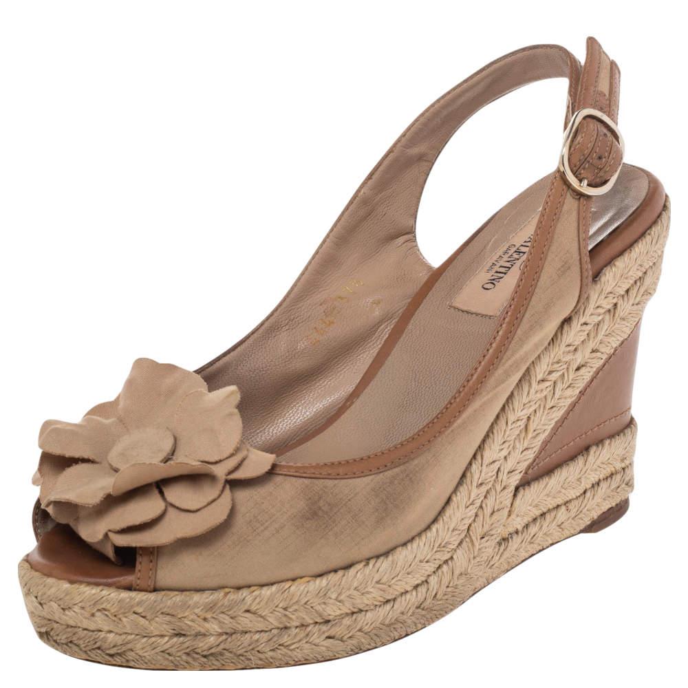 Chic and contemporary, these Valentino sandals are simply amazing! They have been crafted from beige fabric and leather and feature a peep-toe silhouette. They flaunt flower details on the uppers and slingbacks with buckle fastenings. Endowed with