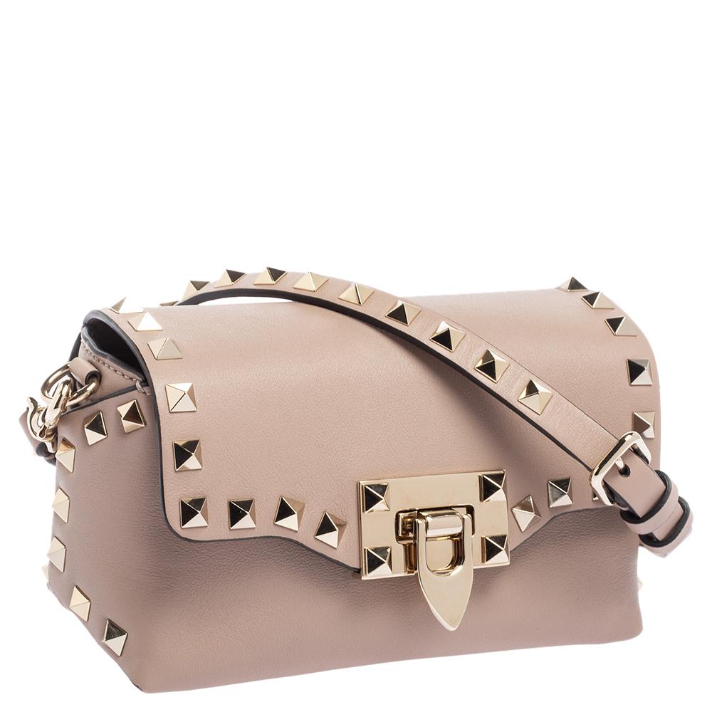 Featuring a chic silhouette highlighted with iconic Rockstud accents, this mini Rockstud shoulder bag from the House of Valentino will make you look fabulous. It is made from beige leather and flaunts gold-toned hardware, a leather-lined interior,