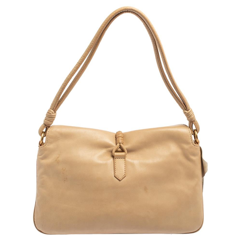 Chic and functional, this bag from Valentino is a piece you must own! It is crafted from beige leather and styled with a V logo charm on the front and floral applique on the front. Highlighted with gold-tone hardware, it opens to a fabric-lined