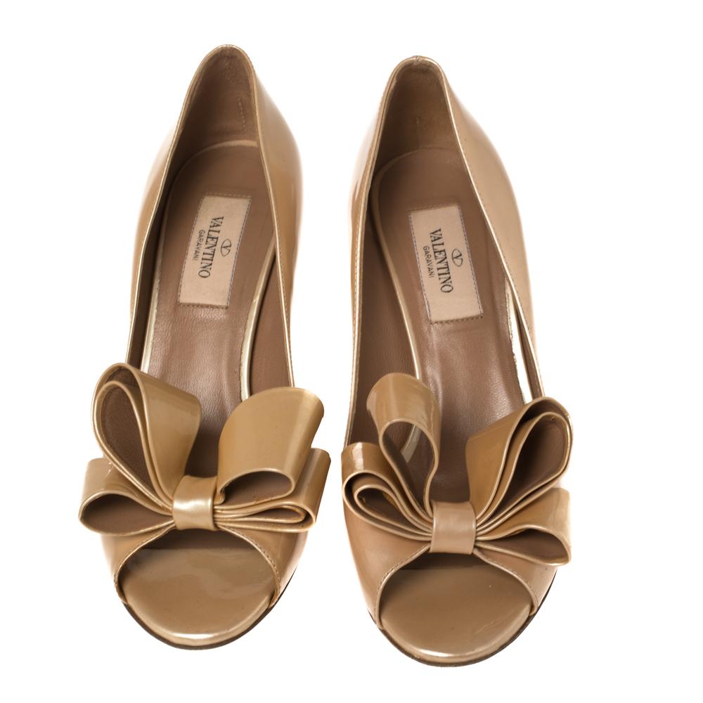 Create an aura of elegance with these peep-toe pumps from Valentino. These beige pumps are crafted from patent leather and feature a sophisticated silhouette. The pair flaunts a bow detailing at the front, leather-lined insoles, and a 7 cm heel.
