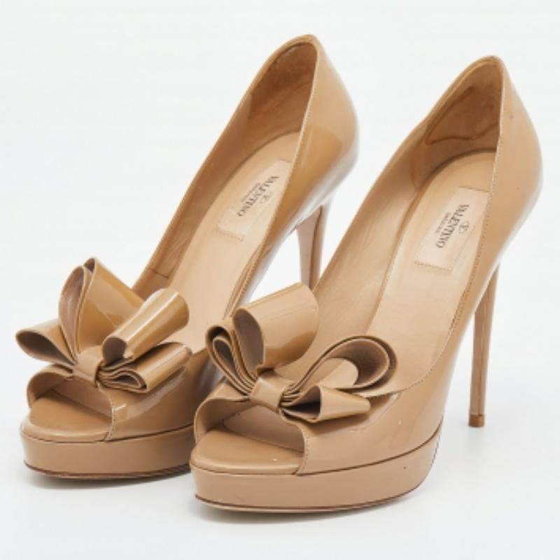 Estos zapatos de tacón de Valentino te ayudarán a dar cada paso con confianza y gracia. Están creados en charol beige y lucen un lazo en la parte delantera. Lucen plataformas, tacones altos y un estilo slip-on. Lleva tu estilo unos centímetros más