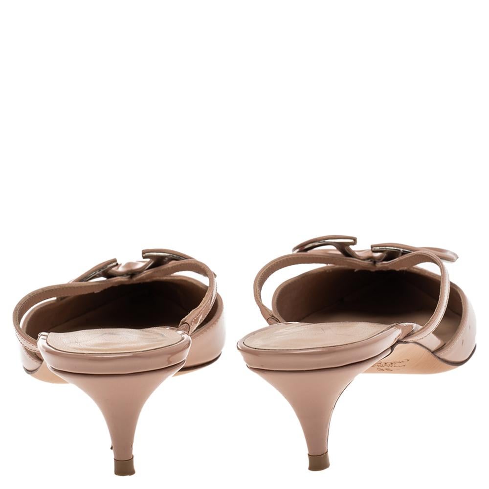 If you are an admirer of the latest fashion trends, this pair of Valentino mules will add just the right vibe to your closet. The pointed-toe patent leather mules are covered in a stunning beige hue and detailed with the V logo on the uppers and