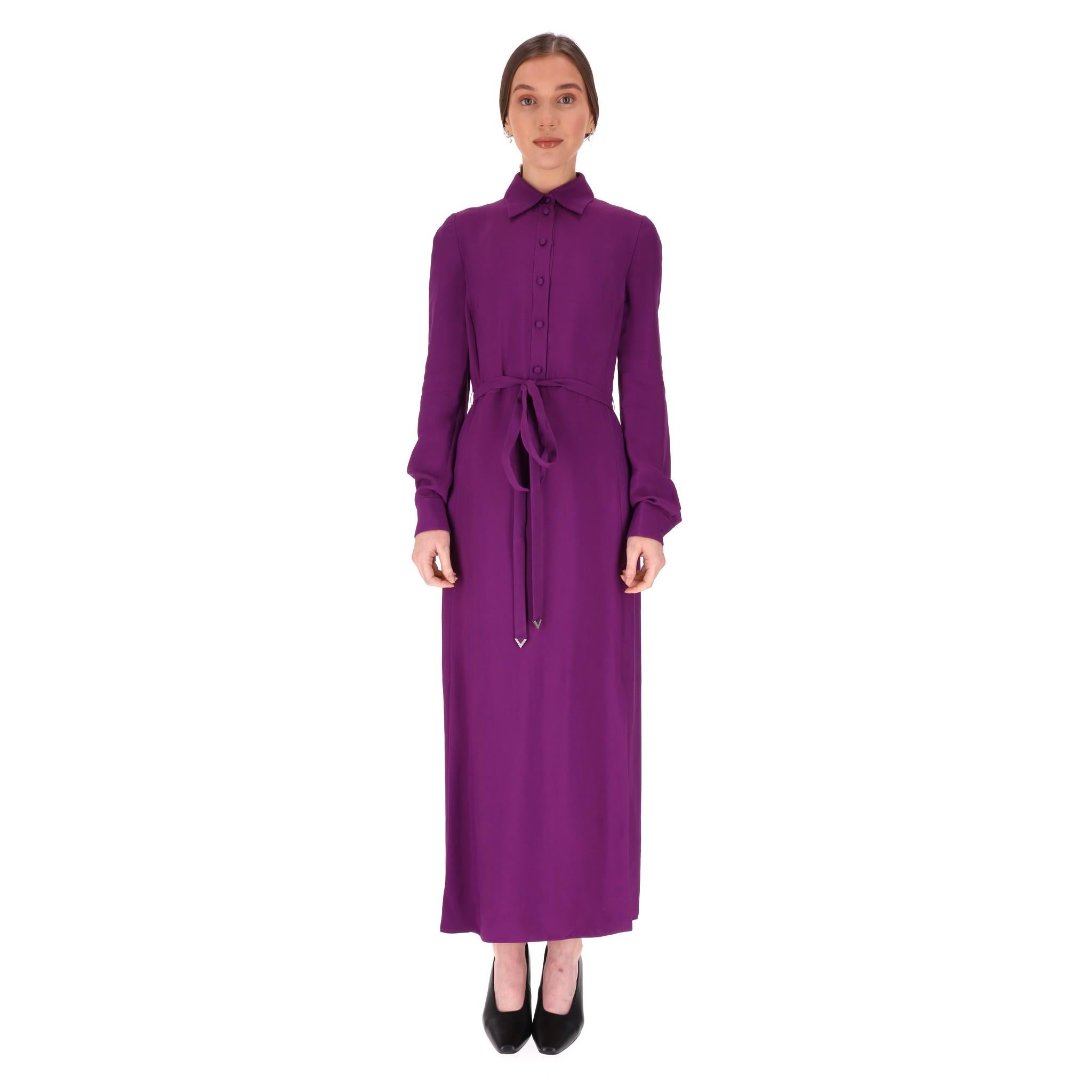 Valentino Belted Crepe Maxi Dress

Purple maxi shirtdress featuring classic collar and long sleeves with buttoned cuffs and front button closure.

Self tie silk belt to the waist, finished at the bottom with a silver 'V-shape' logo with crystal