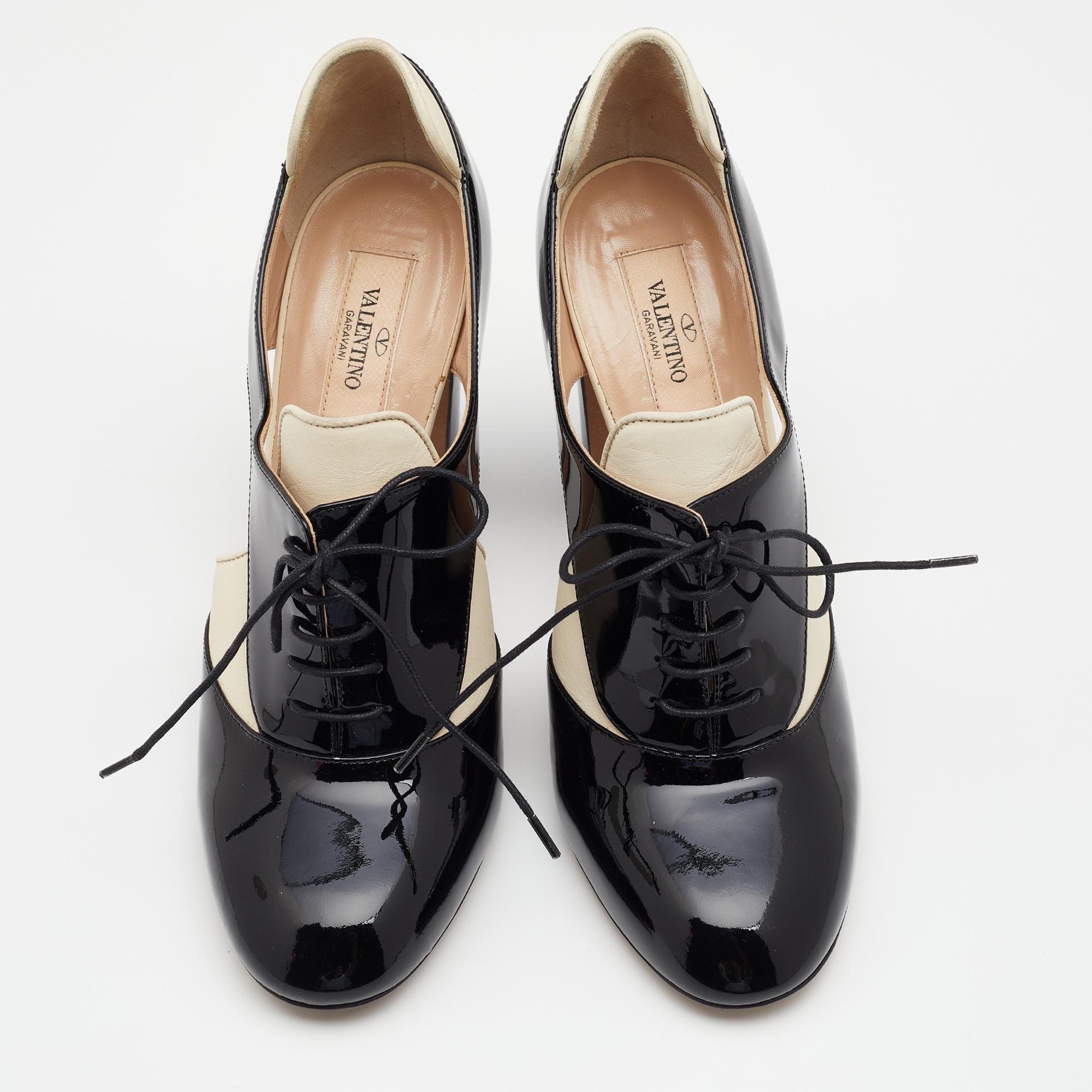 Valentino presents a modern, feminine reinterpretation of the Spectator shoes. These patent and leather pumps feature 10.5 cm block heels and contrasting black-cream hues. With lace-up detailing and cut-outs, they present the perfect amalgamation of