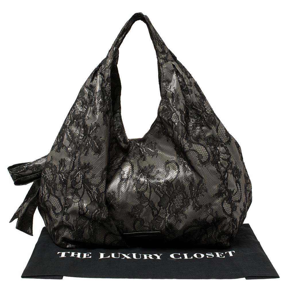 Look elegant and chic with this Valentino hobo. It is very unique with a black lace exterior and an oversized bow on the side. Its slouchy structure makes it perfect for day to night events, featuring a placard in the front with Valentino’s logo