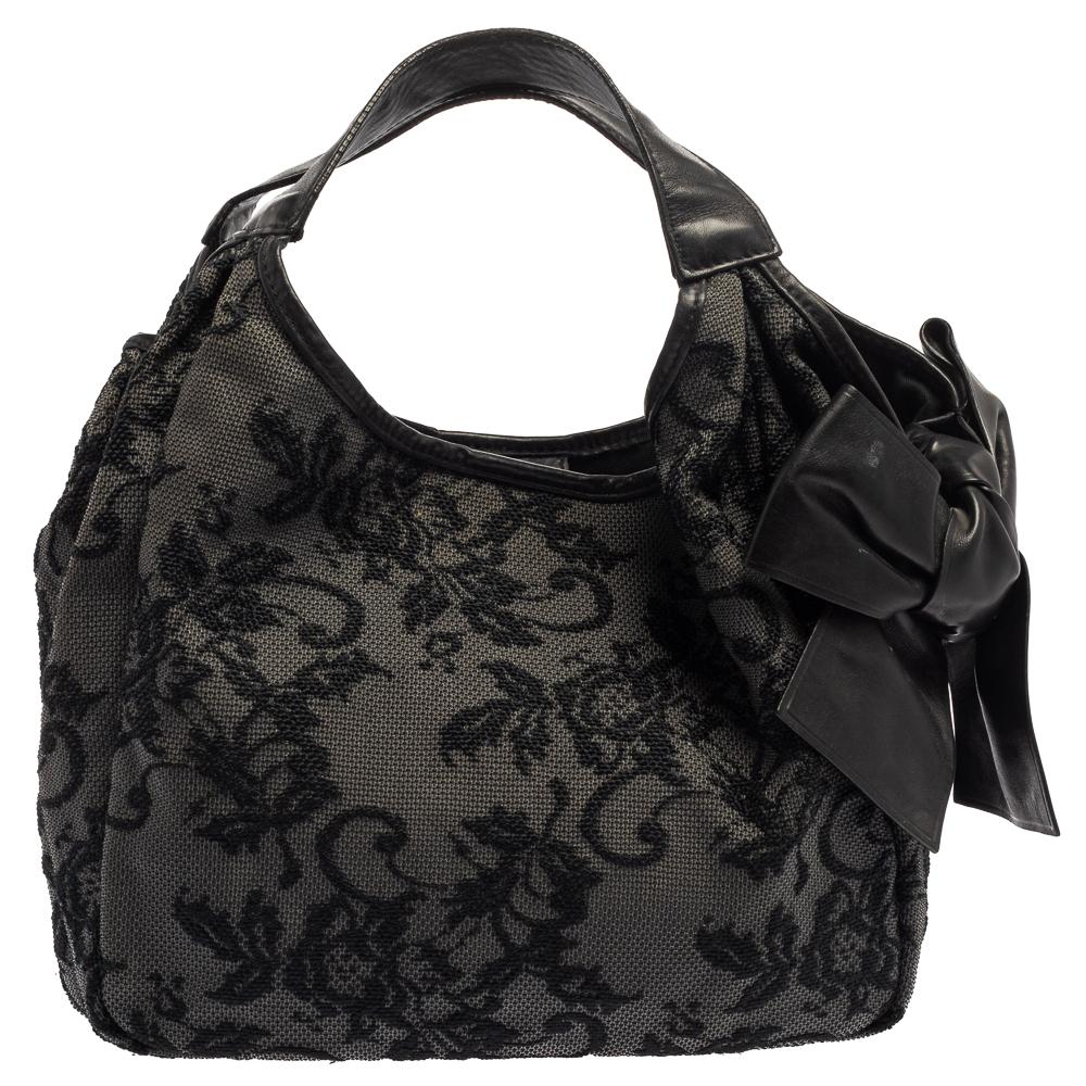 Look elegant and chic with this Valentino black hobo. It is very unique with a black nylon exterior and an oversized bow on the side. Its slouchy structure makes it perfect for day to night events, featuring a gold-tone placard in the front with