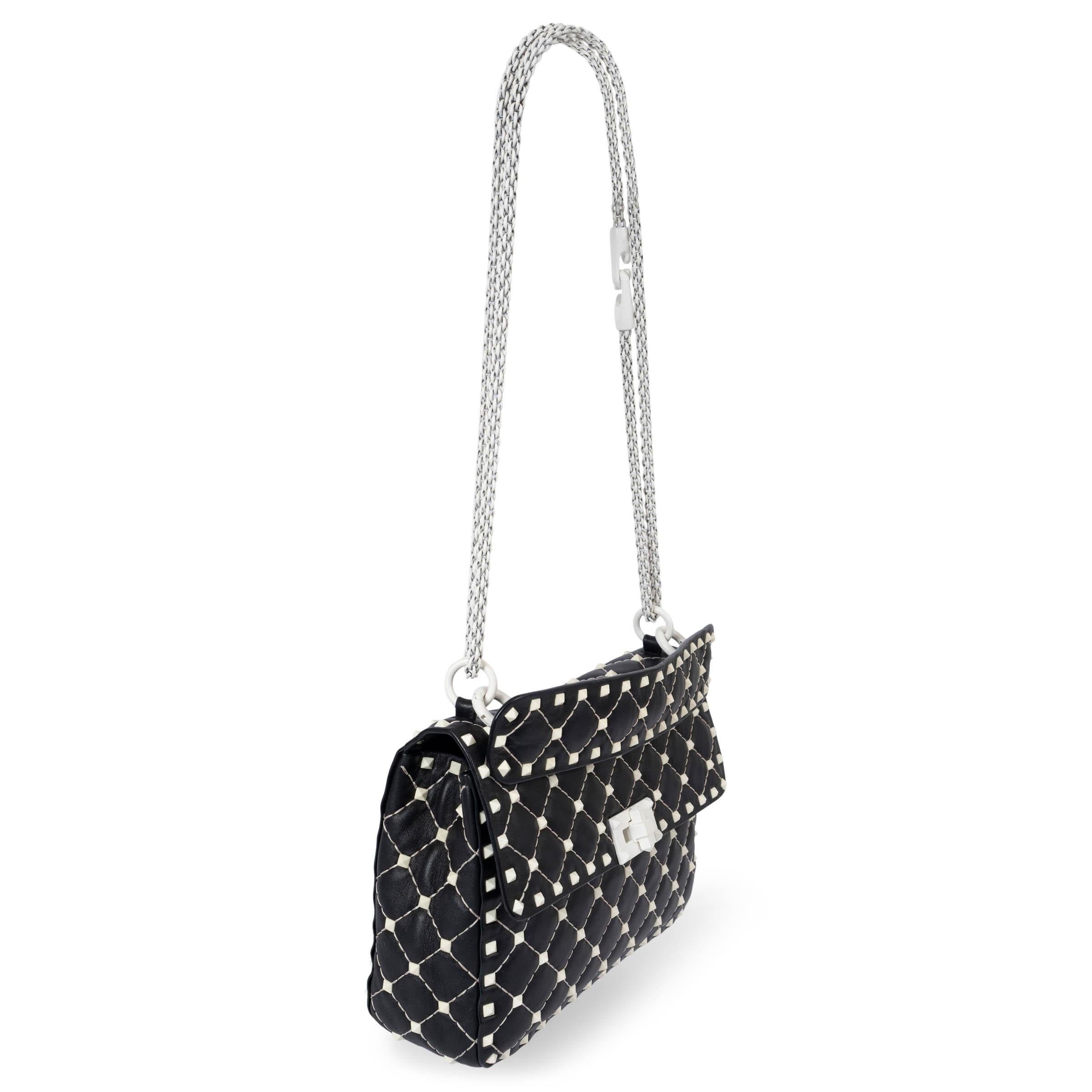 100% authentique Valentino Free Rockstud Spike Small shoulder bag en cuir lisse noir et rehaussé de micro clous blancs. Le modèle est doté d'une poignée supérieure amovible et d'une sangle en chaîne blanche. Doublé de cuir noir et rouge, il est doté