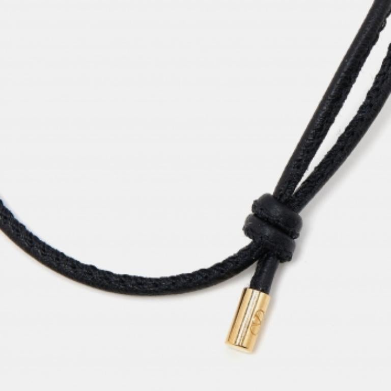 Sencilla, con clase, atemporal. Valentino te trae esta pulsera negra de piel con detalles de metal dorado en las puntas. Es ajustable para adaptarse a cualquier tamaño de muñeca.