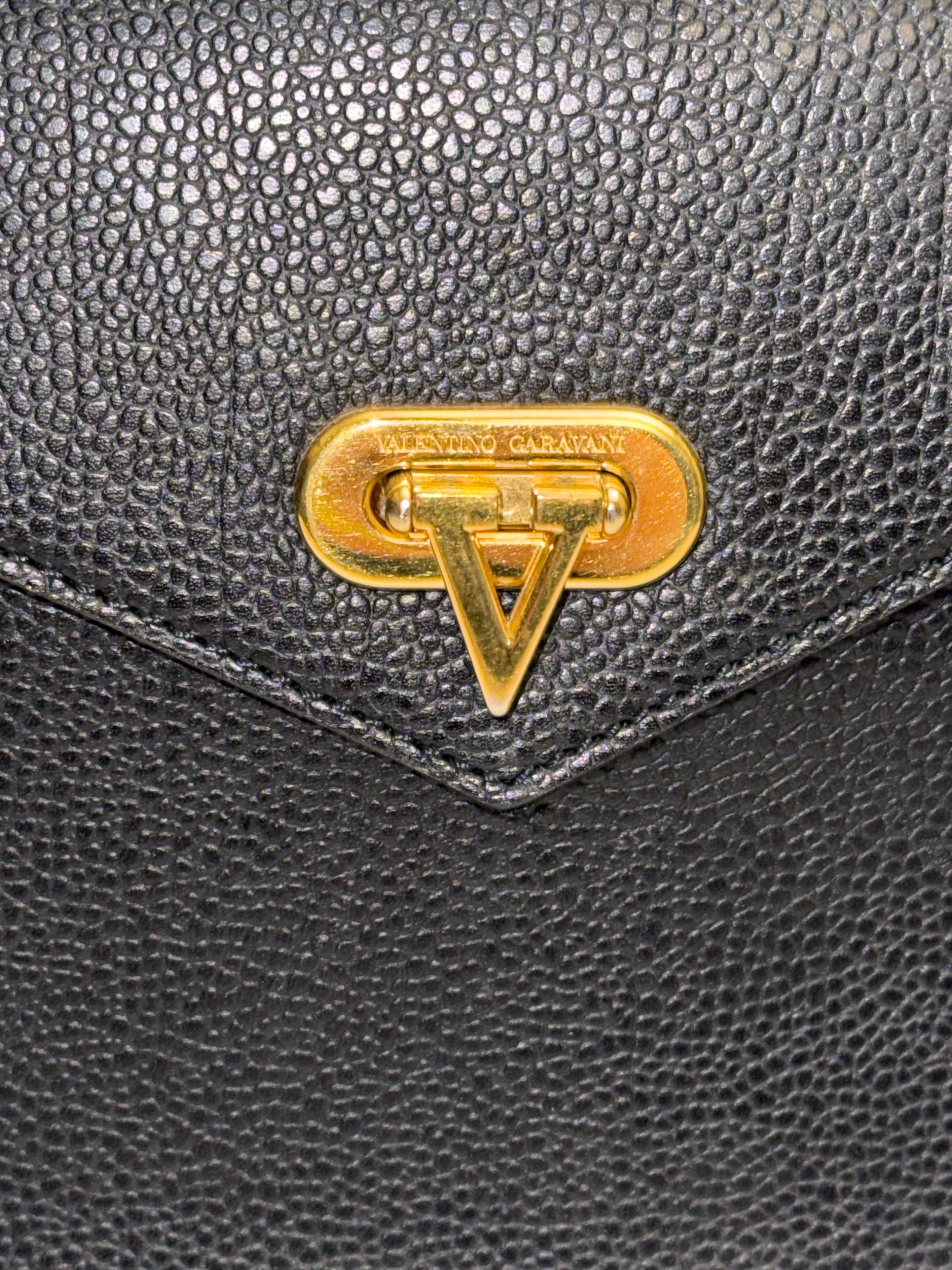 - Vintage Valentino black leather handbag. Chic, elegant and timeless!

- Featuring V shape gold toned hardware buckle closure. 

- V monogram interior linging. 

- One interior zip pocket closure. 

- Length: 10 inches. Width: 4 inches. Height: 7.5