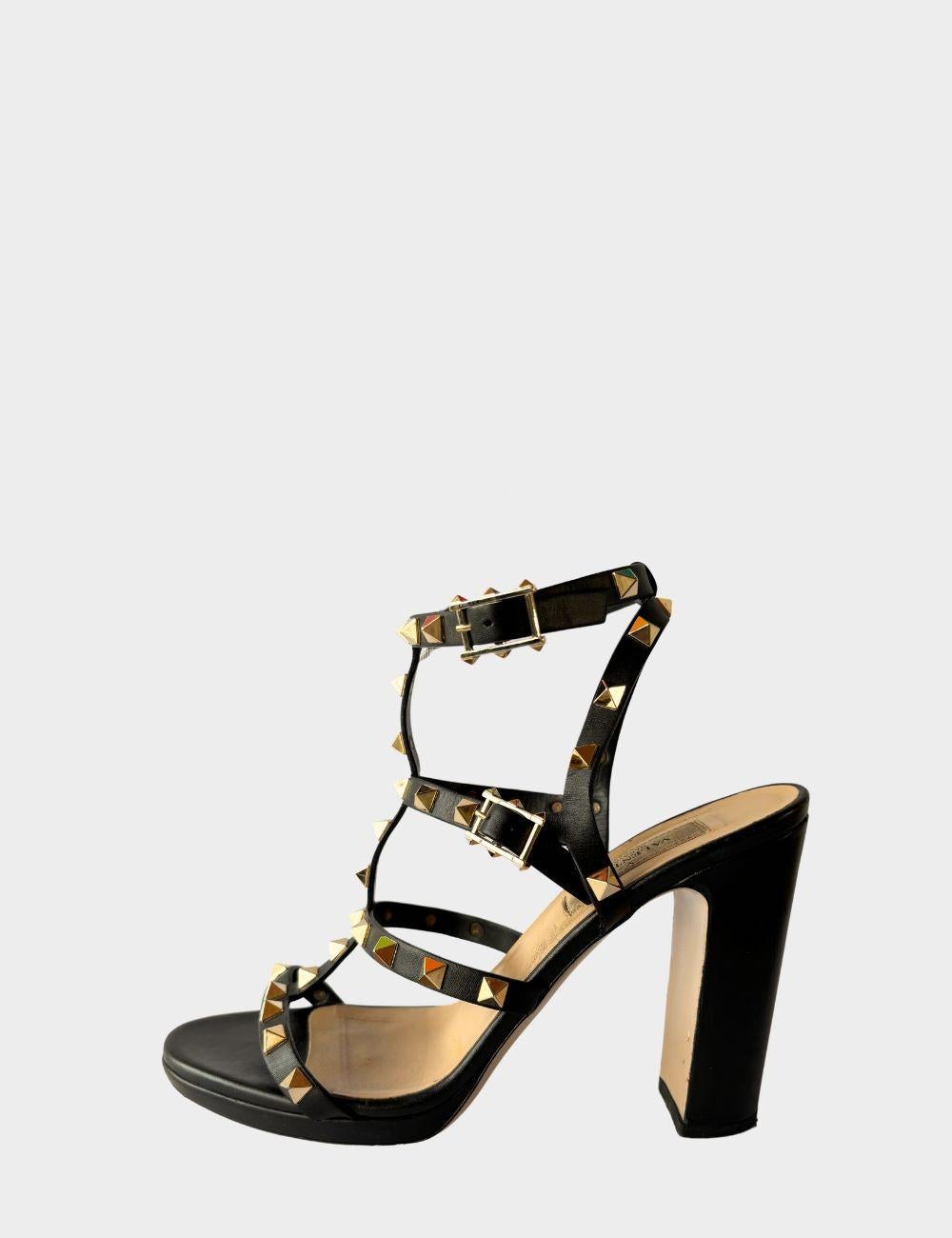 Make a bold statement with these iconic Valentino Rockstud sandals. Crafted from luxurious black leather, these strappy block heel sandals are adorned with the brand’s signature gold-tone pyramid studs. Featuring multiple adjustable straps and a