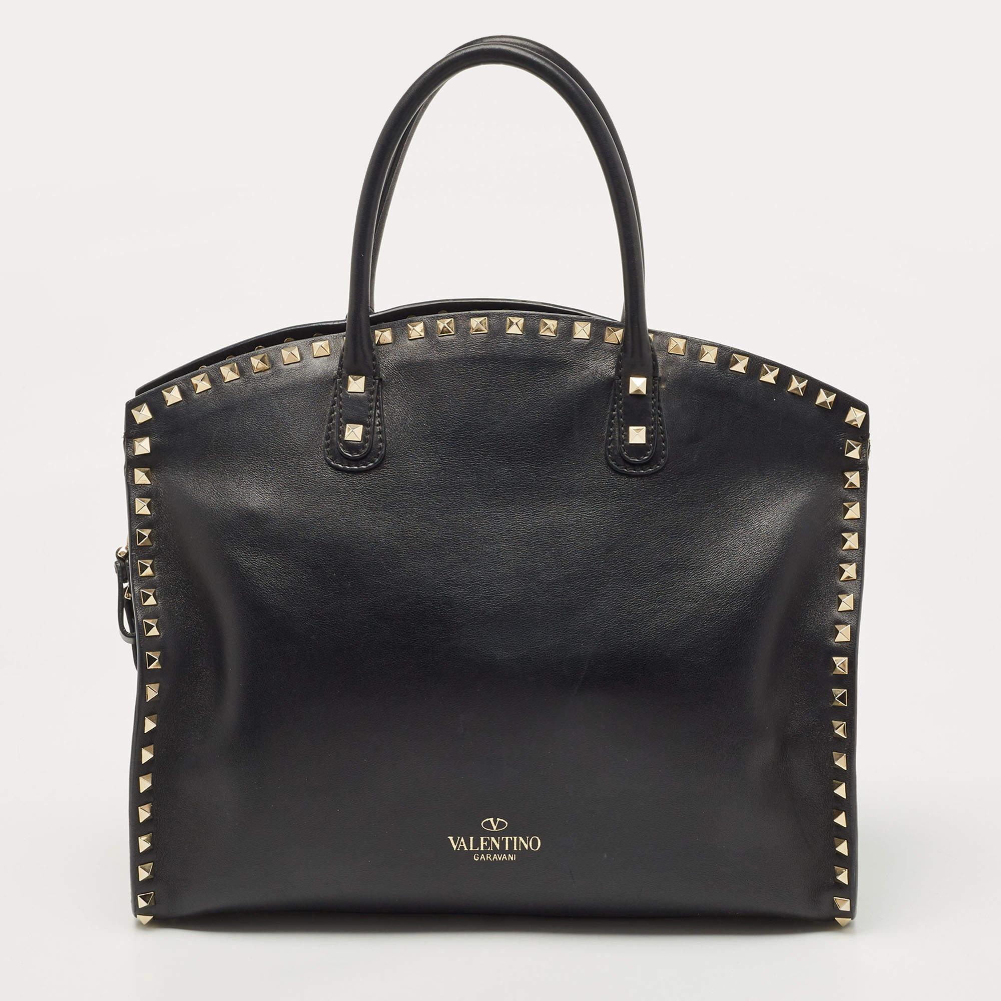Rock chic and fab, this bag by Valentino means business. Made from black leather in a dome shape, it comes accented with signature Rockstud outlined in gold-tone hardware. It features top rolled handles with an optional shoulder strap. The bottom