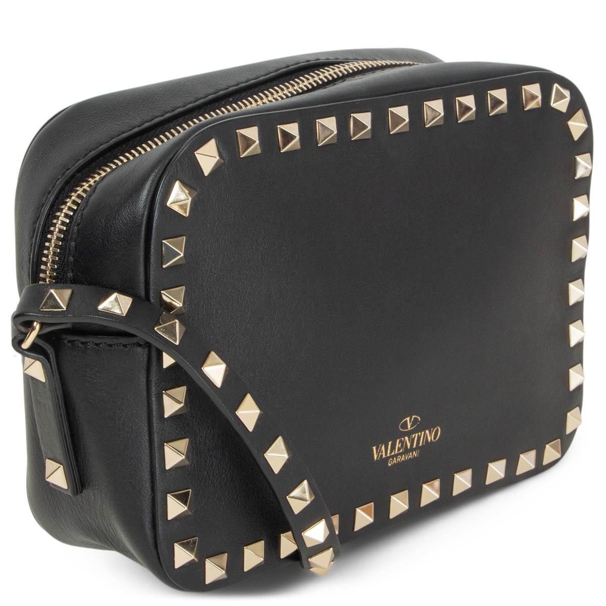 100% authentic Valentino Rockstud mini camera cross body camera bag in black leather with light gold-tone singnature  studs. Opens with a zipper on top and is lined in black canvas with one open pocket against the back. Has a adjustable shoulder