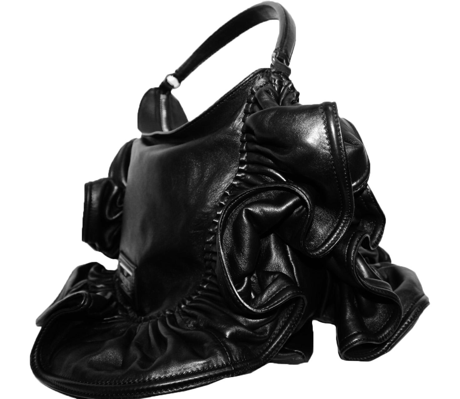 Valentino black leather ruffle frame bag includes a single covered top handle.  This bag is lined in silver tone silk fabric with one side zippered pocket with silk Valentino tag in red.  The bag resembles a Valentino ruffled skirt composed of 