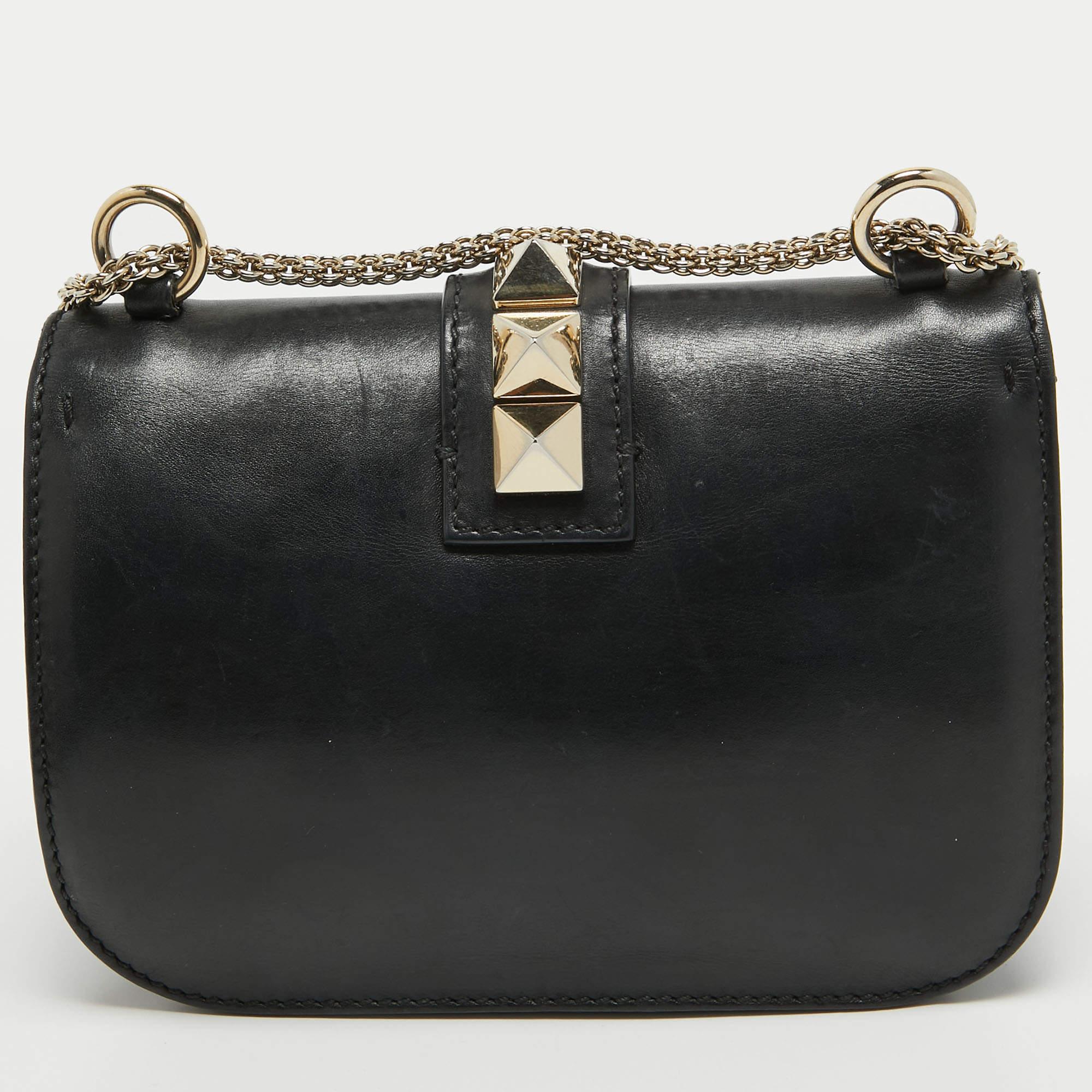 If you are looking for a bag that presents ageless style, this Valentino creation is the answer. Crafted from leather in a black shade, this piece comes with a slender chain strap and a flap with a push-lock to secure the well-sized interior. The