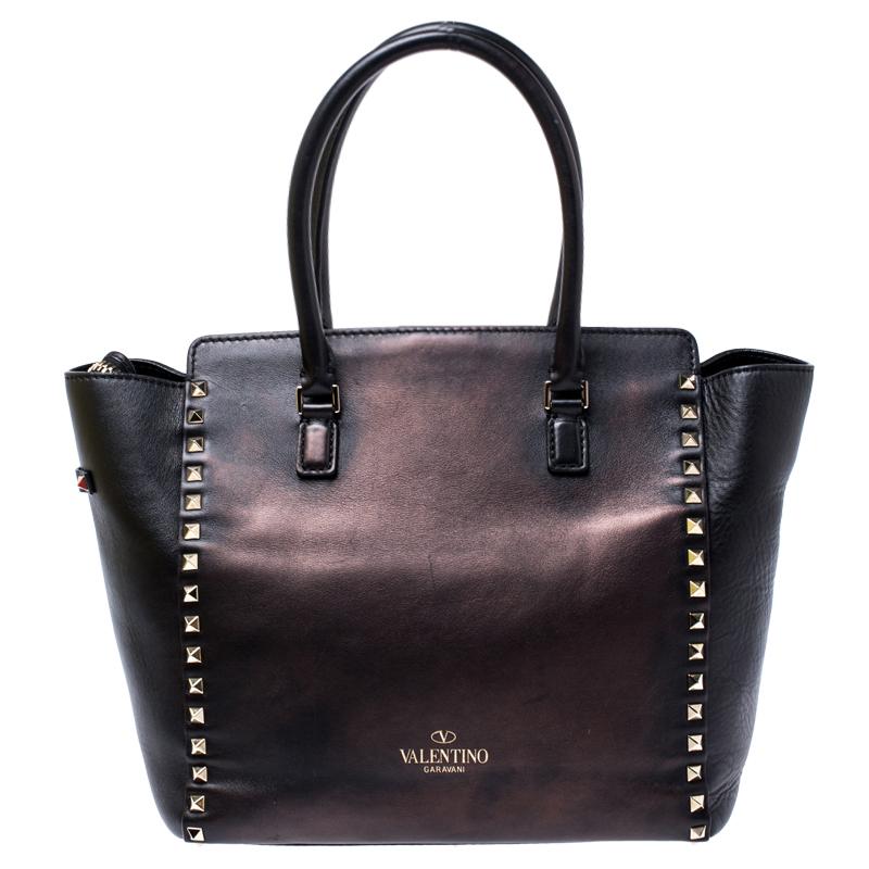 Valentino brings you this super-stylish tote that carries a design which will surely grab the attention of your onlookers. It has a classy black exterior decorated with the signature pyramid Rockstuds. The leather tote is complete with a spacious
