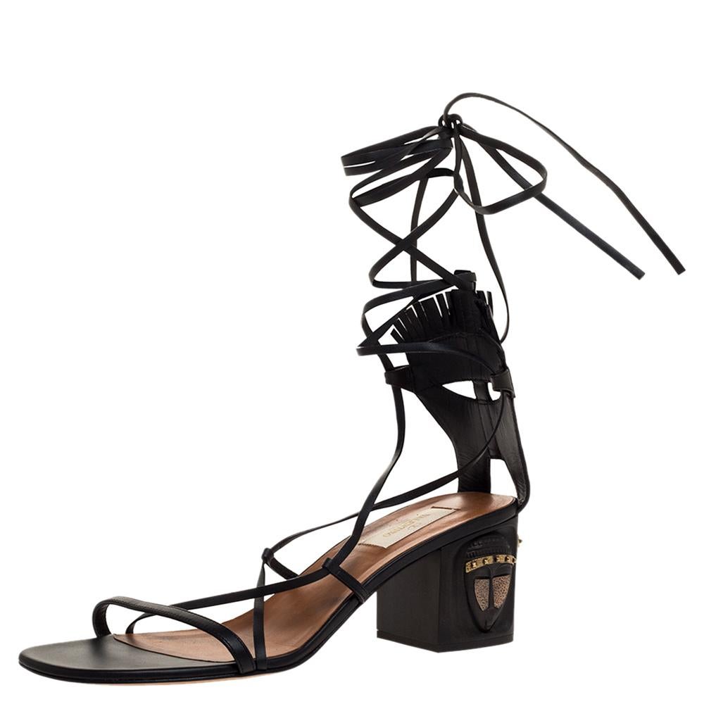 A perfect mix of elegant fashion and sensuous style, these Valentino sandals come crafted from leather and designed with lace-ups that end as a self-tie at the ankles. They're visually stunning and they stand atop block heels featuring tribal mask