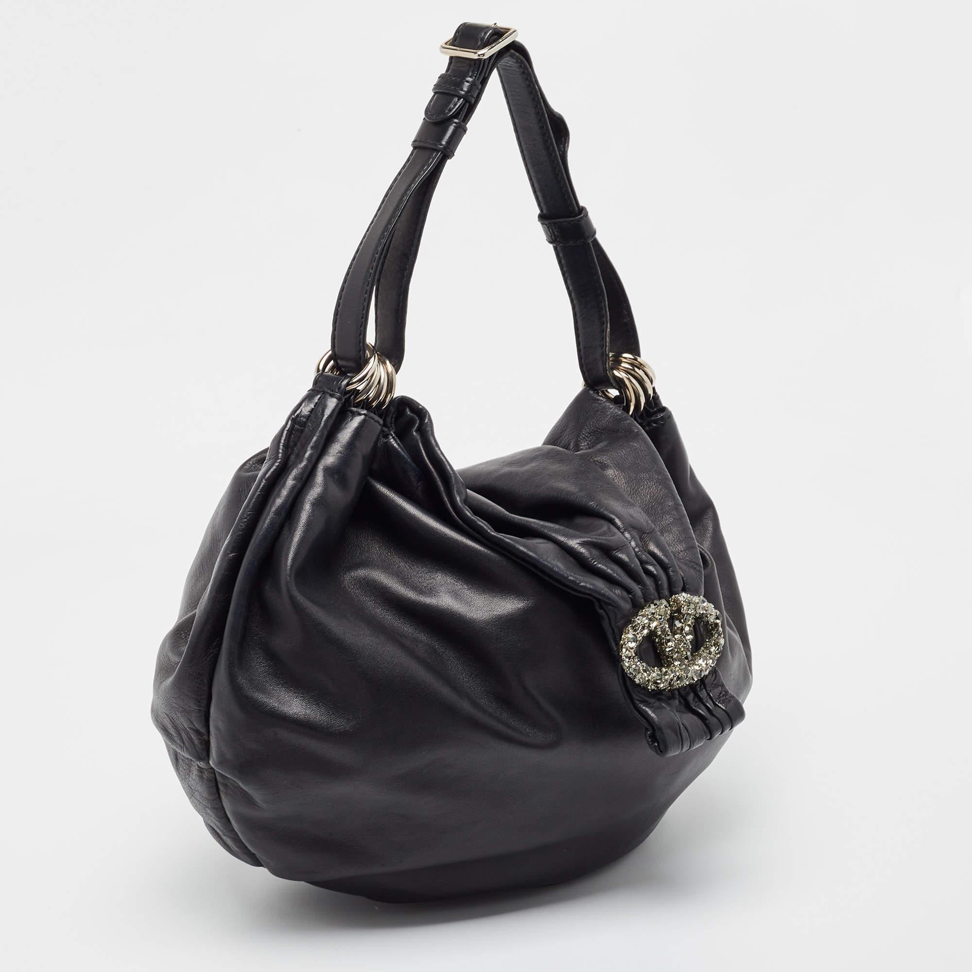 El bolso de piel de Valentino es una creación bellamente cosida. La parte delantera está decorada con el emblemático logotipo en V de la marca y la cremallera superior se abre para revelar un interior bien forrado. Llévala en la mano o sujétala al