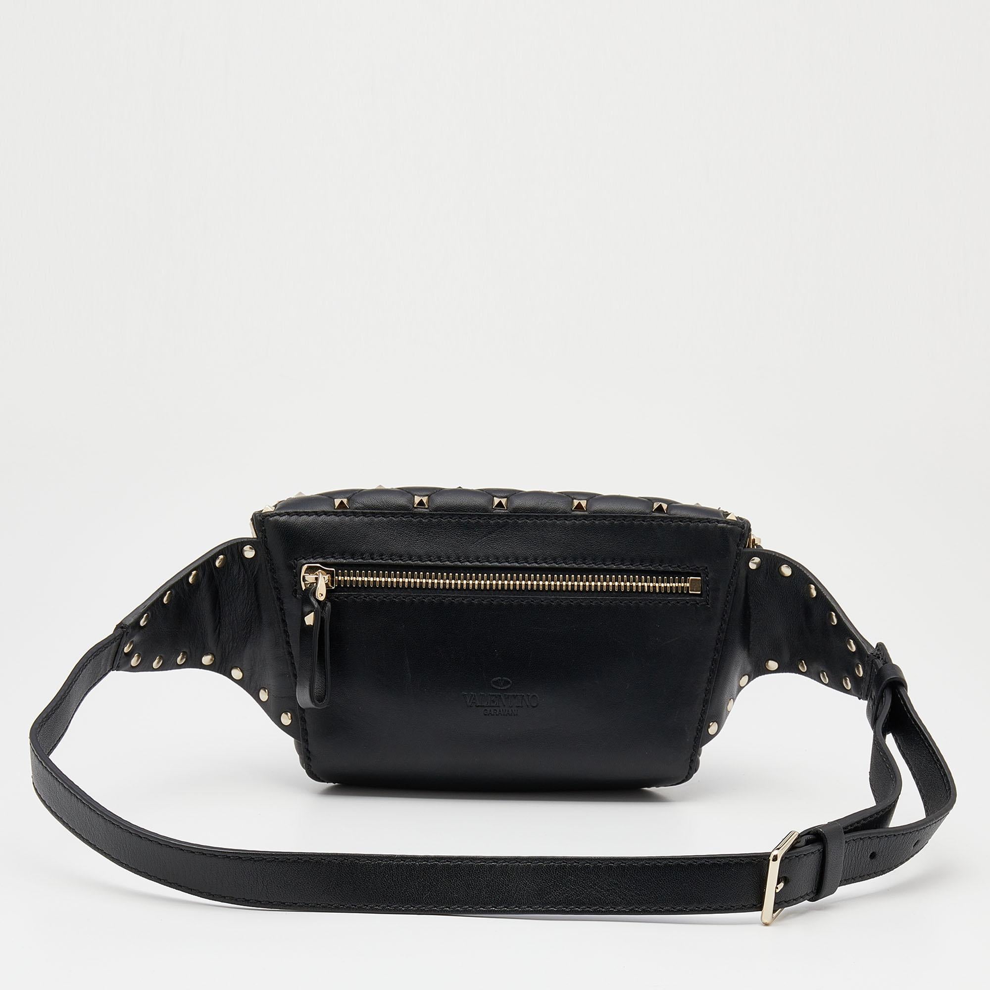 How cute is this belt bag from the House of Valentino! Fashioned in black leather, this belt bag is accentuated with Rockstud embellishments throughout. It flaunts a zipper on the front, which leads us to the leather-lined interior. Gold-tone