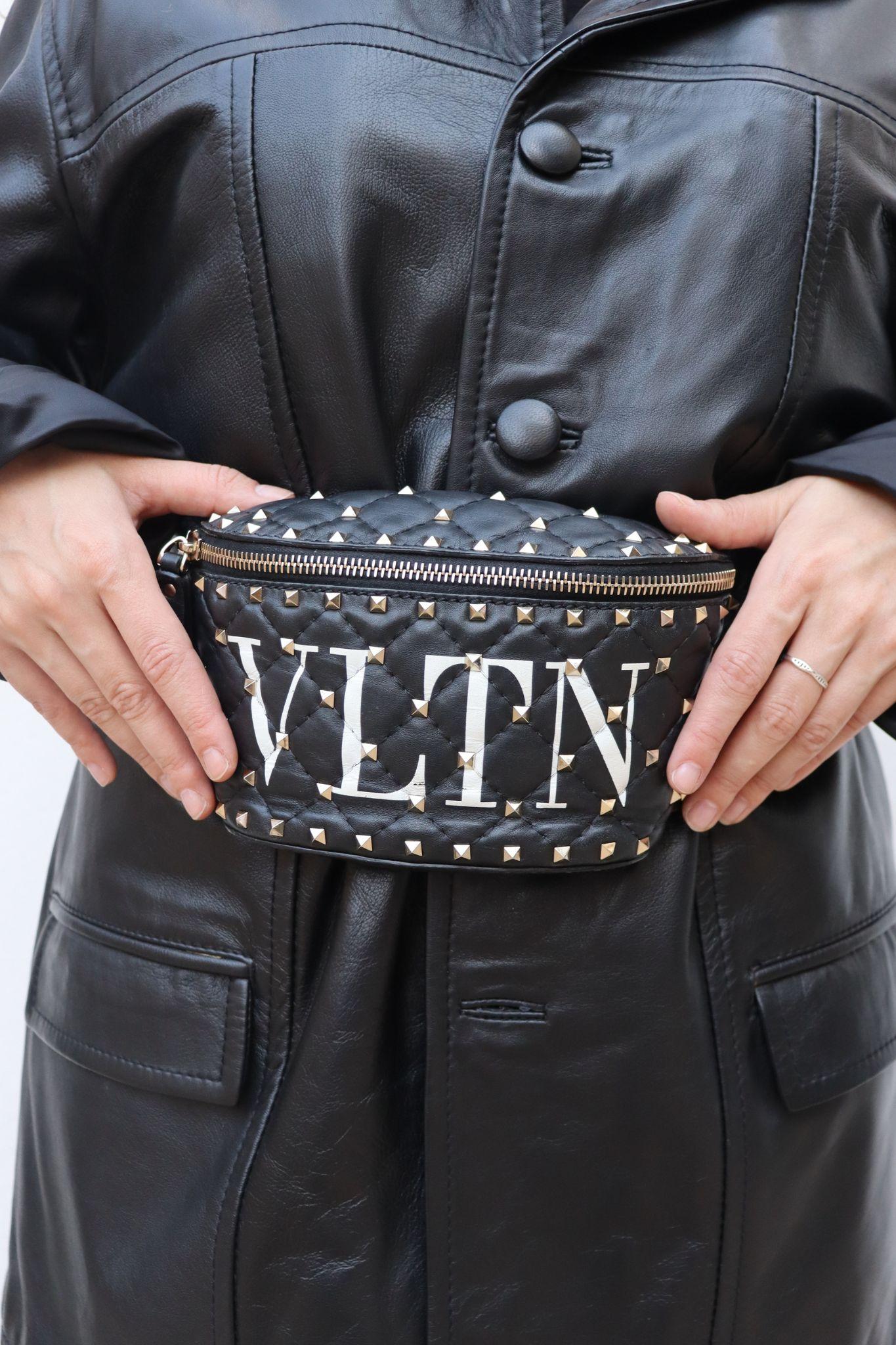 Valentino Black Leather VLTN Rockstud Bum Bag, comporte des embellissements Rockstud, une fermeture éclair sur le devant et un intérieur doublé de cuir.

MATERIAL : Cuir.
Quincaillerie : Or.
Hauteur : 11cm
Largeur : 20cm / Dessus
Profondeur :