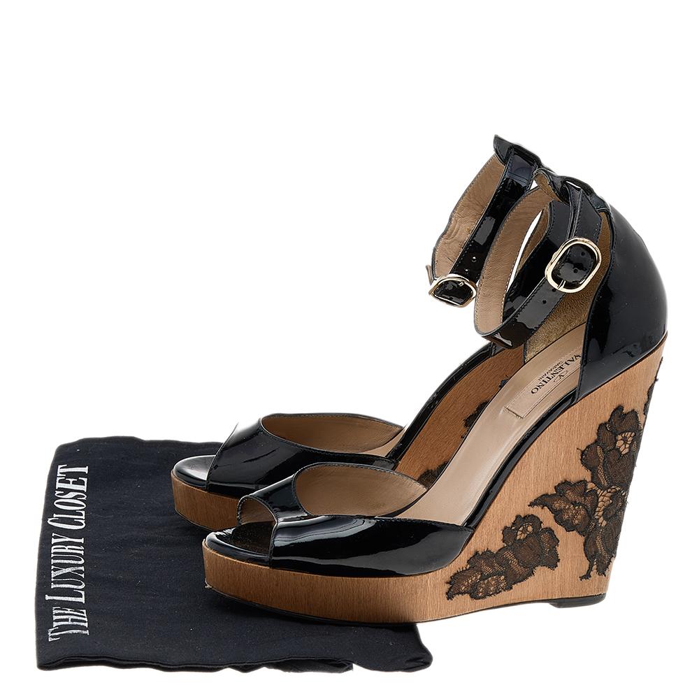 Comfort and fashion join hands in these lovely sandals from Valentino. These black sandals are crafted from patent leather and feature peep toes, covered counters with ankle fastening, comfortable leather-lined insoles, and lace-embellished wedge
