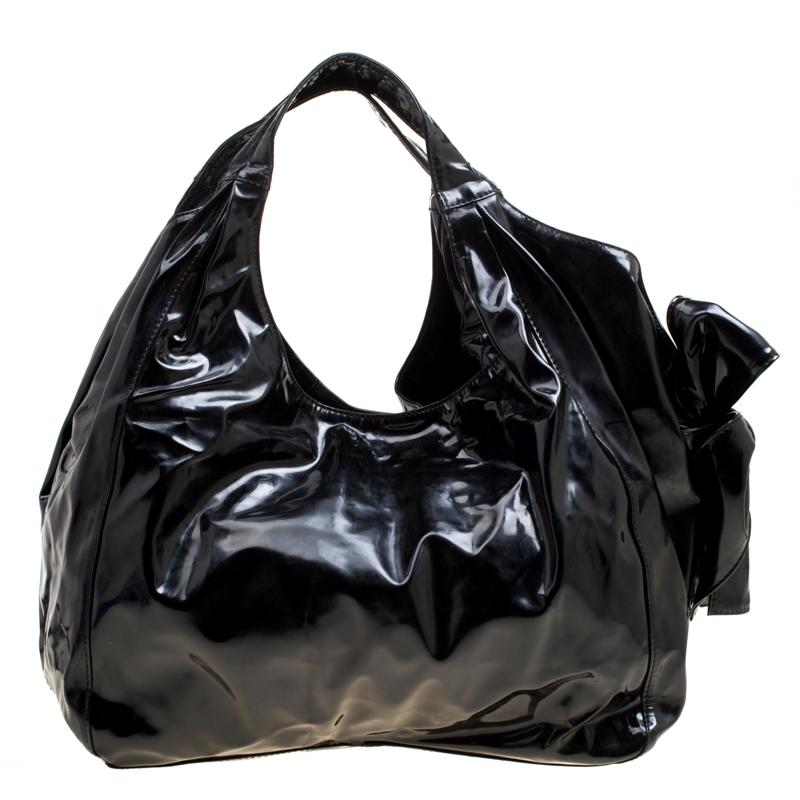 Nothing is more subtly charming than black patent leather, and this bag is no exception. The signature Valentino bow sits proudly and prominently at the side of this Nuage bow tote. A gold-tone logo plate is showcased on the bottom back while the