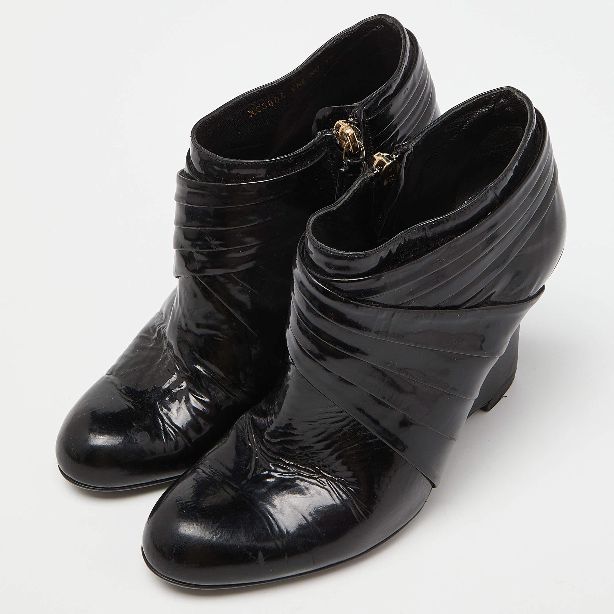 Donnez une touche chic à votre tenue avec cette paire de bottines Valentino. La création est parfaitement cousue en cuir verni et montée sur des talons compensés. Faites-vous remarquer avec ces