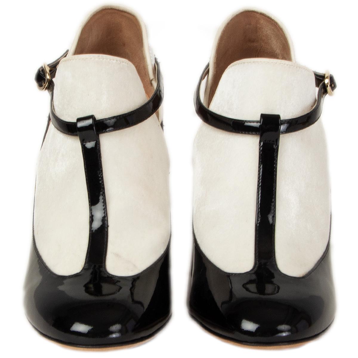 100% authentic Valentino T-Bar pumps in white velvet and black patent leather. Close with a buckle on the side. Have been worn with a faint stain at the right shoe's front part and on the side. Overall in very good condition.
