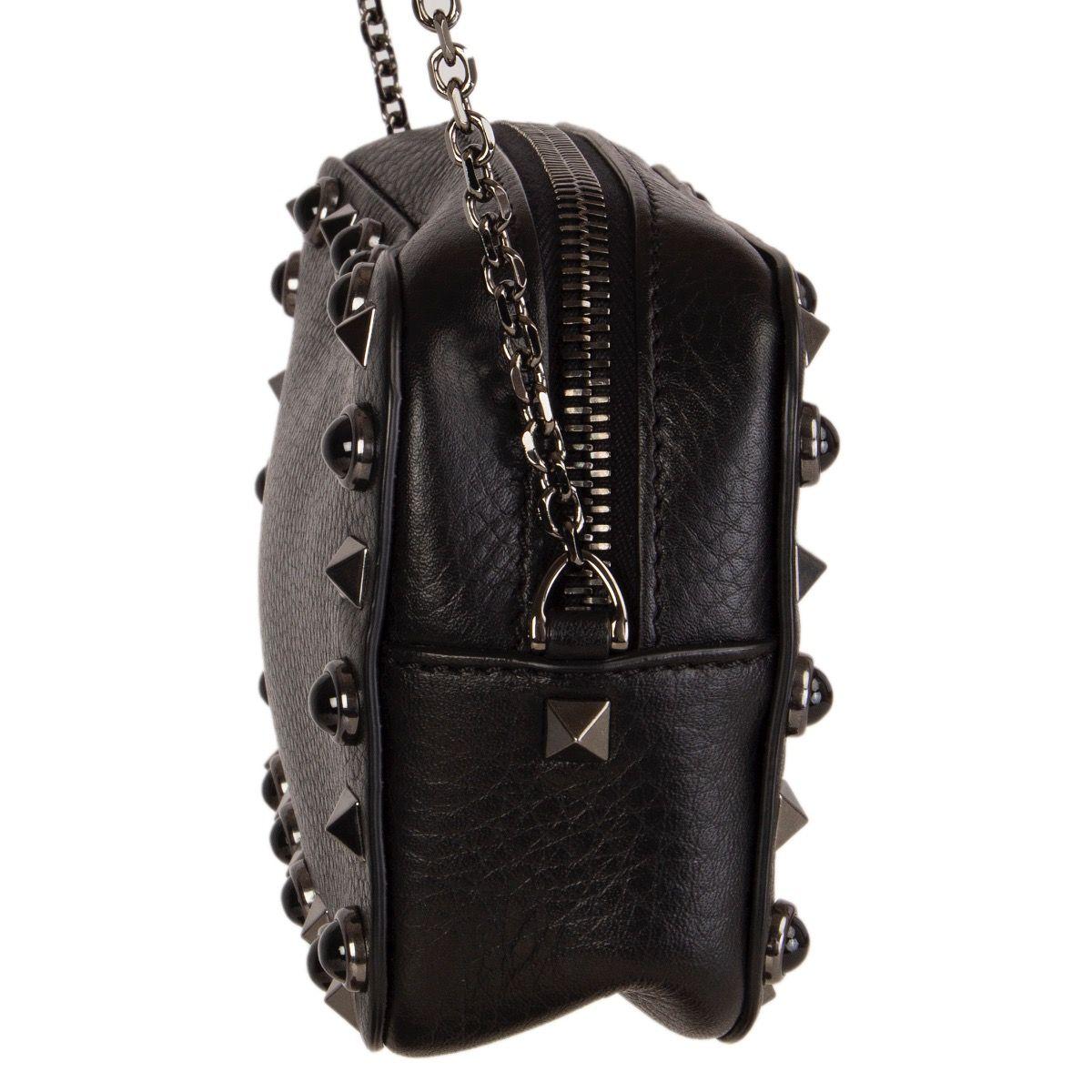 Valentino 'Rockstud Rolling Small Chain' crossbody camera bag in black grained calfskin embellished with signature pyramide studs and black stones. Opens with a zipper on top and has one open pocket against the back. Has been carried and is in