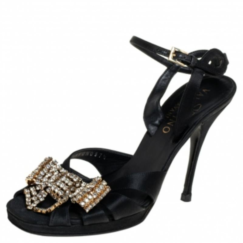 These stunning sandals by Valentino are made from black satin. They are adorned with crystal-embellished bows on the uppers for an opulent finish. Secured with ankle straps, these sandals are set on 8.5 cm heels.