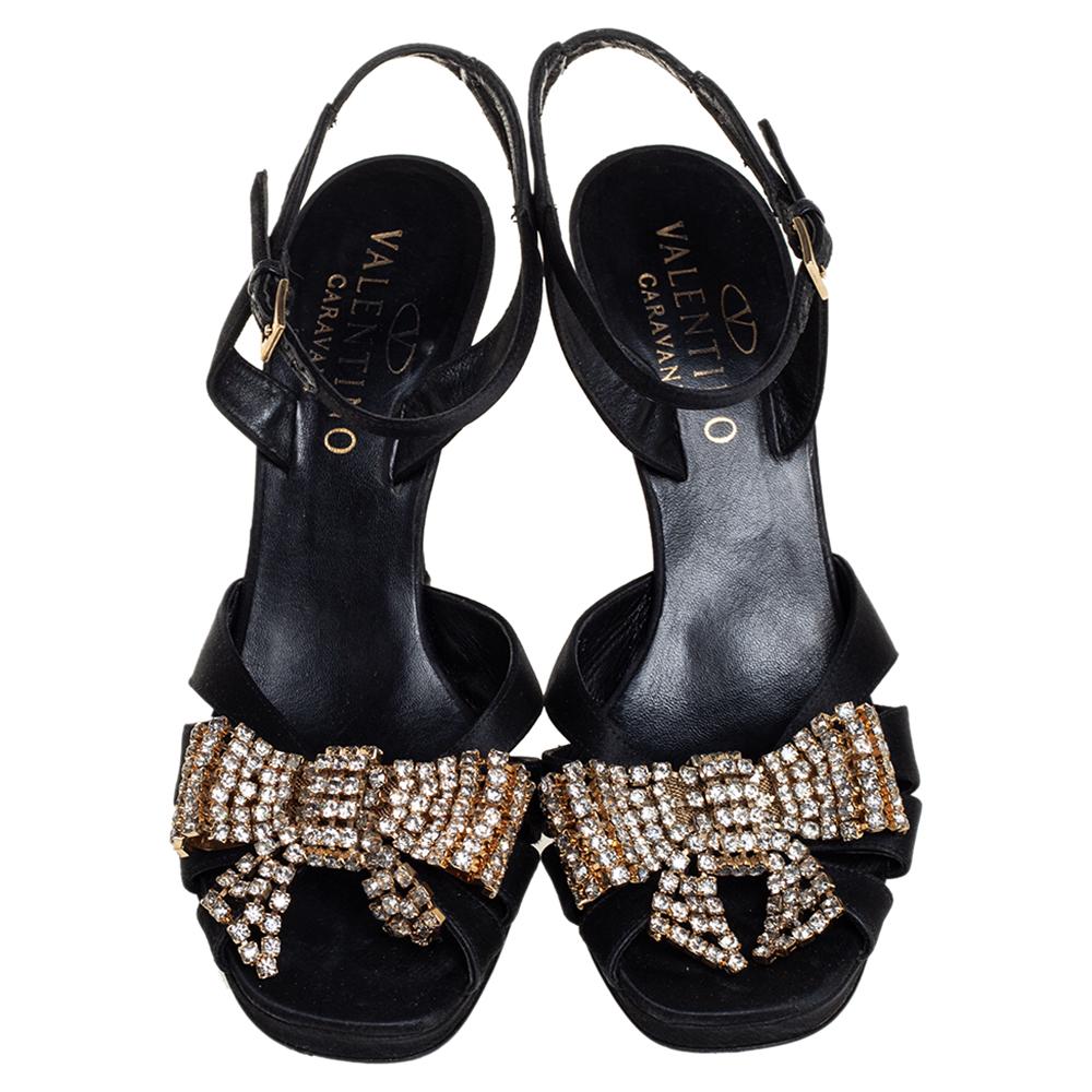 These stunning sandals by Valentino are made from black satin. They are adorned with crystal-embellished bows on the uppers for an opulent finish. Secured with ankle straps, these sandals are set on 8.5 cm heels.

