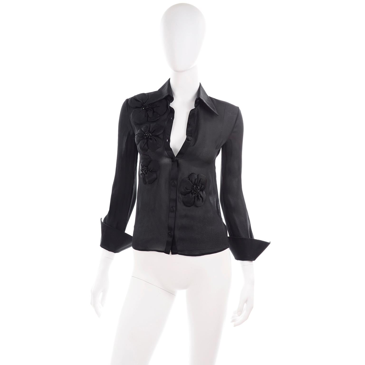 This is a truly stunning black sheer silk chiffon Valentino blouse with silk satin cuffs, collar, placket, buttons, and floral rosette appliques. The beautiful black beads in the center of the flowers give an additional pop of detail! This is