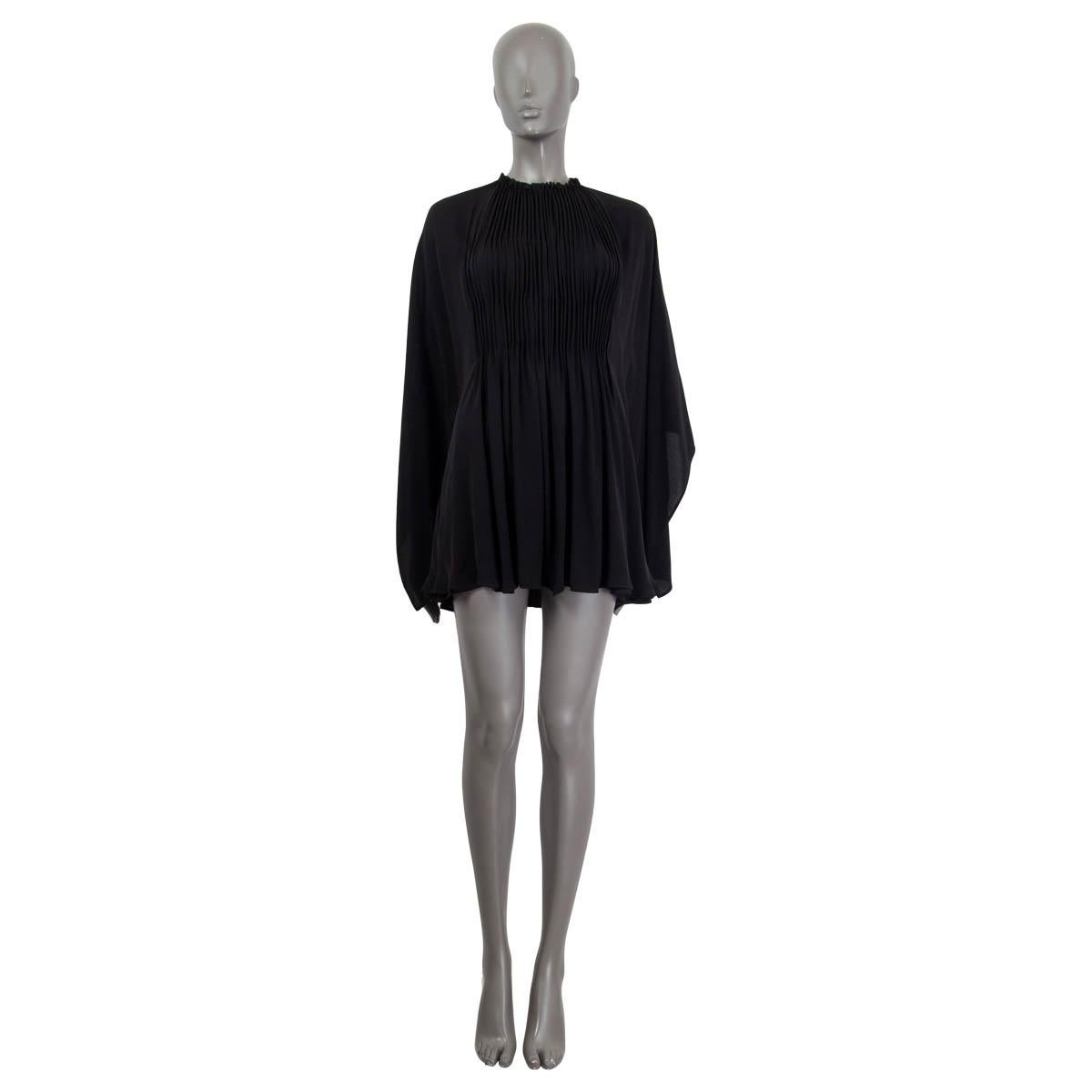 100% authentic Valentino oversized pleated mini dress in black silk (100%). Features open sleeves and a high gathered collar. Opens with a button on the neck. The attached slip dress in black silk (91%) and elastane (9%) opens with four hooks at the